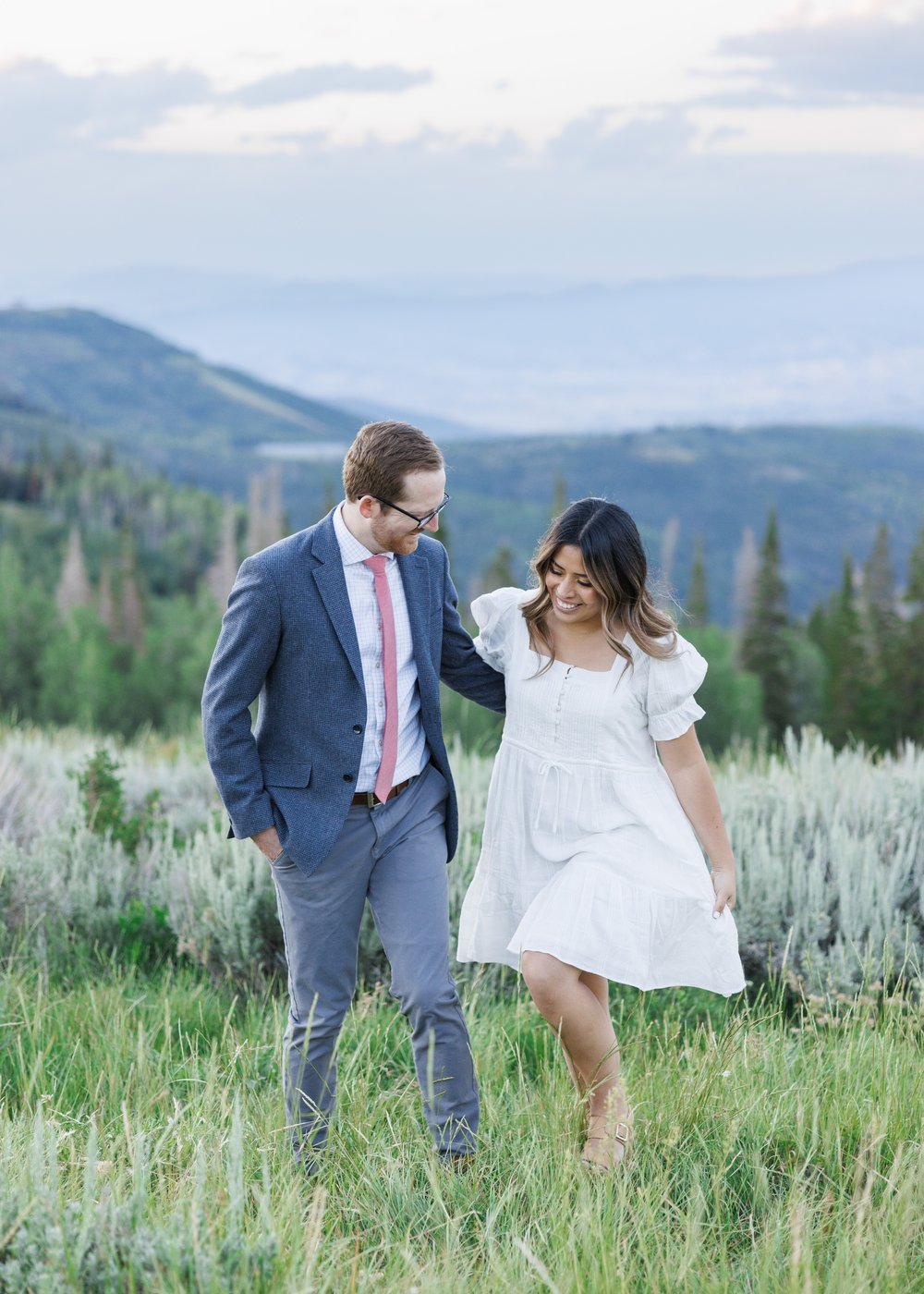  High-end Park City photographer Savanna Richardson Photography captures a woman in a white dress walking on a mountain with her fiance. Mountain #ParkCityEngagements #ParkCityPhotographers #SavannaRichardsonPhotography #SavannaRichardsonEngagements 