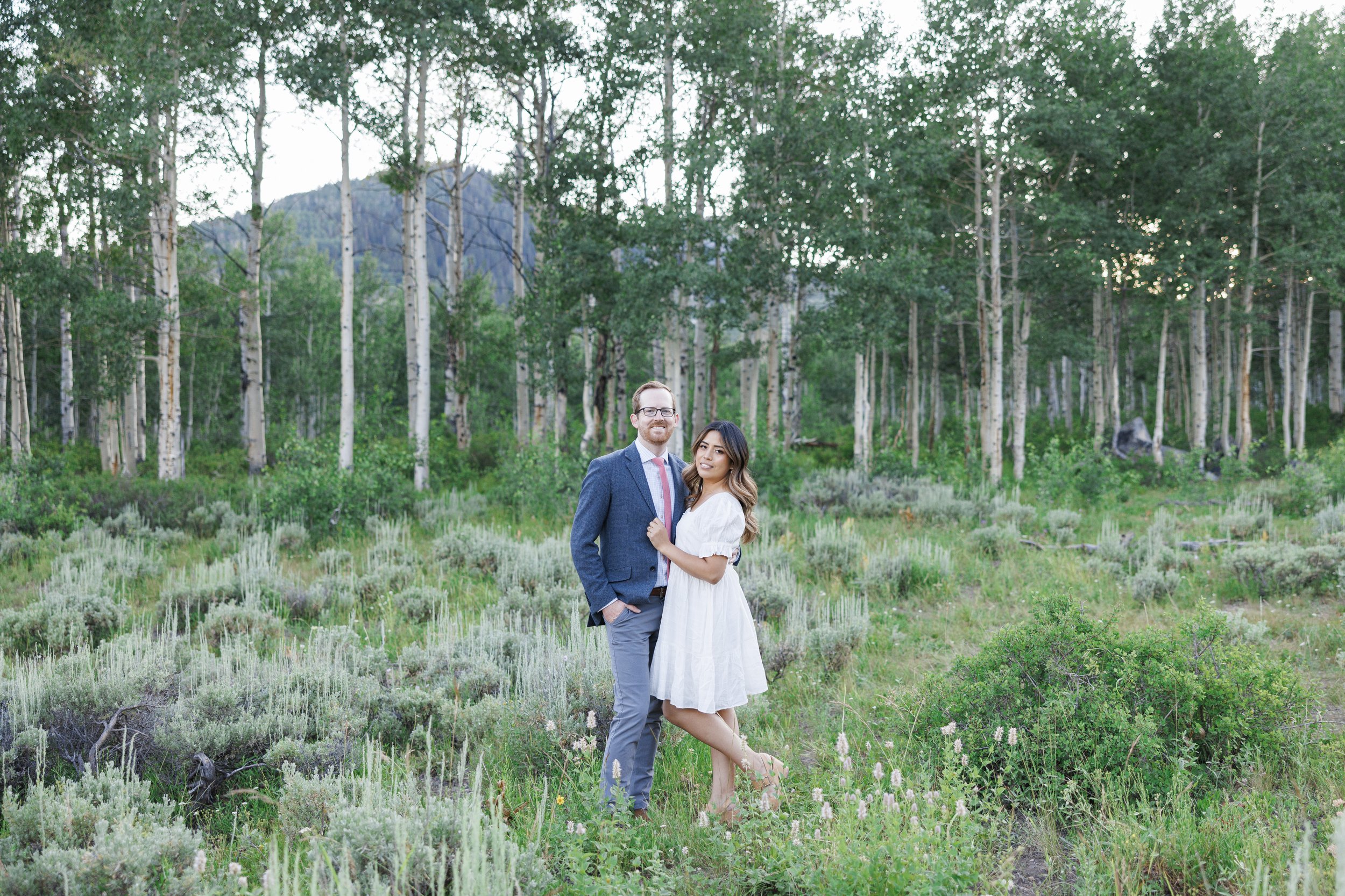  On the Park City mountainside, an engaged couple smile among the sagebrush by Savanna Richardson Photography. green mountain engagement ideas #ParkCityEngagements #ParkCityPhotographers #SavannaRichardsonPhotography #SavannaRichardsonEngagements 