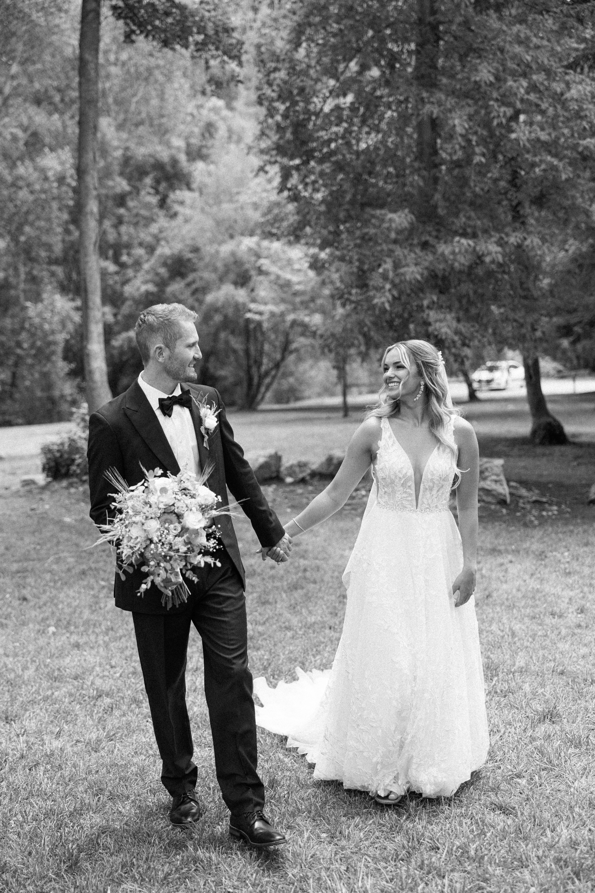  Savanna Richardson Photography captures a black and white portrait of a bride and groom holding hands in a meadow. black and white bridals #SavannaRichardsonPhotography #SavannaRichardsonWeddings #QuietMeadowFarms #MapletonUTweddingphotographers 