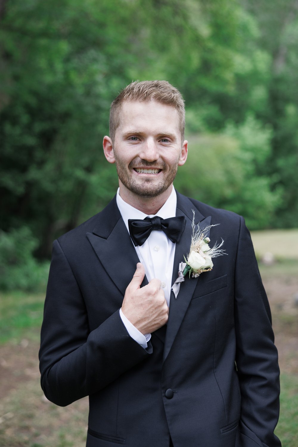  Groom in a black suit and bowtie smiles for a portrait captured by professional Savanna Richardson Photography. Mapleton weddings Utah groom #SavannaRichardsonPhotography #SavannaRichardsonWeddings #QuietMeadowFarms #MapletonUTweddingphotographers 