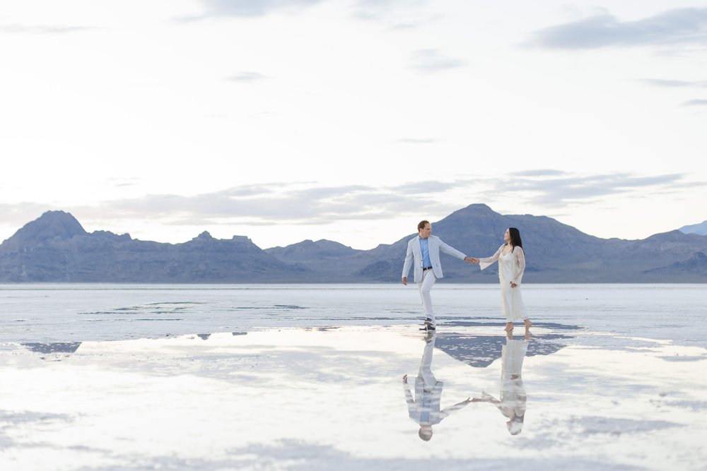  Breathtaking engagement photograph of a couple walking along the water's edge at the salt flats by Savanna Richardson Photography. #SavannaRichardsonPhotography #SavannaRichardsonEngagements #slcweddingphotographers #saltflatengagement #saltflats 