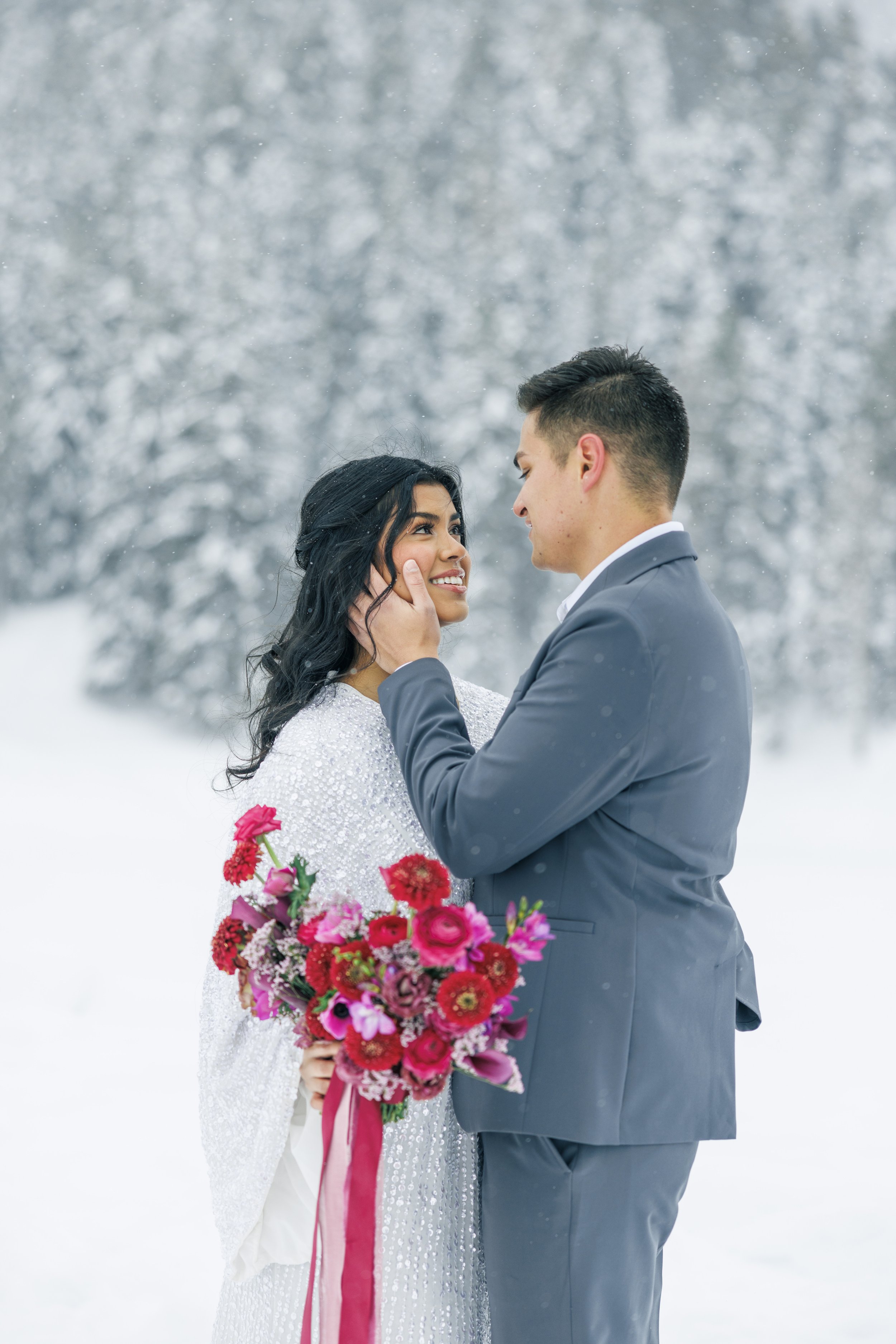  At Tibble Fork, Savanna Richardson Photography captures a groom and bride in the snow-covered mountain. red bouquet #SavannaRichardsonPhotography #SavannaRichardsonBridals #WinterBridals #WinterWedding #TibbleForkBridals #UtahBridals #MountainBridal