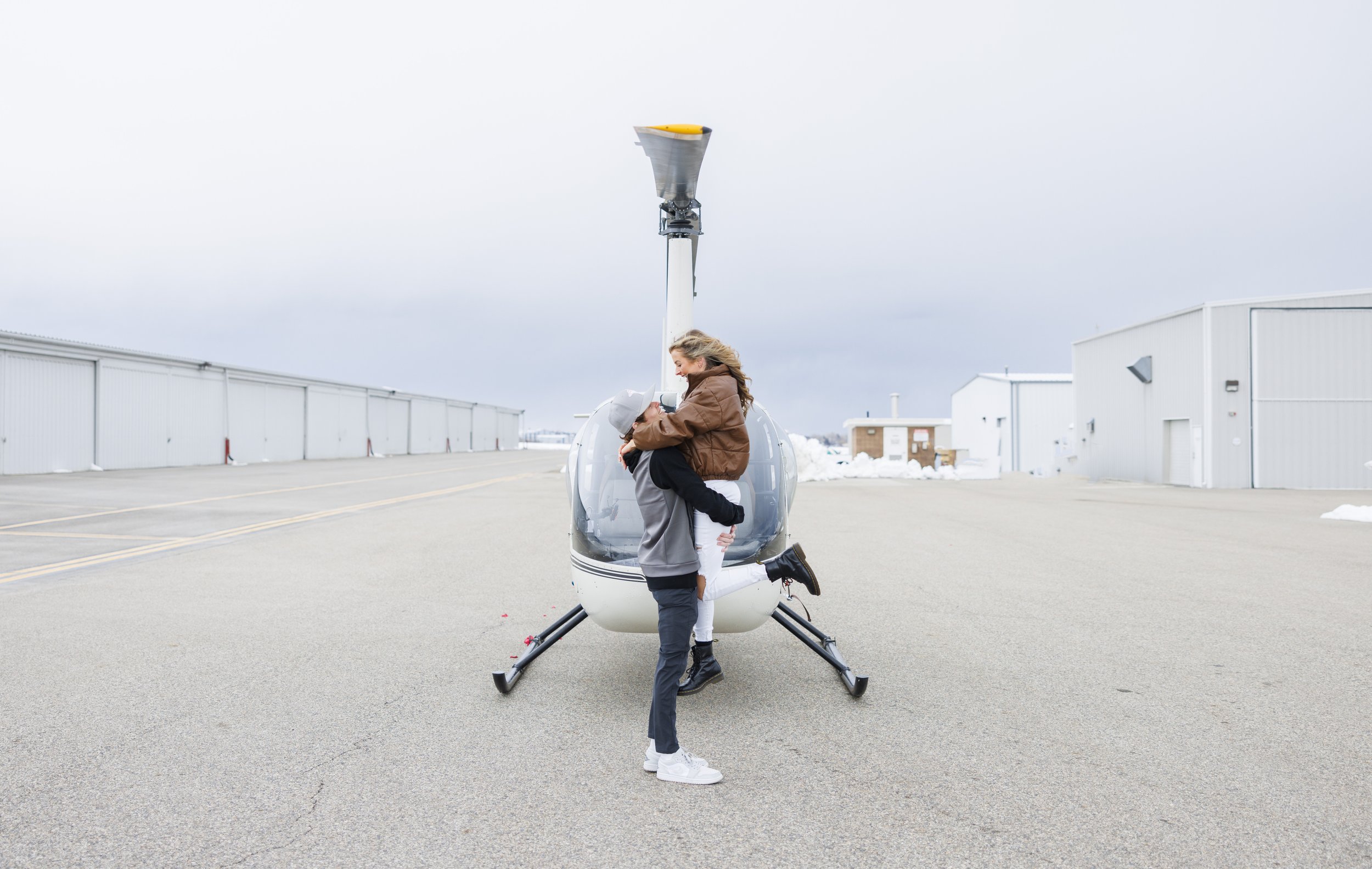  A man lifts his girlfriend up in front of a helicopter for engagements by Savanna Richardson Photography. newly engaged fun engagement locations #SavannaRichardsonPhotography #SavannaRichardsonEngagements #utahproposals #helicopterproposal #Utahenga