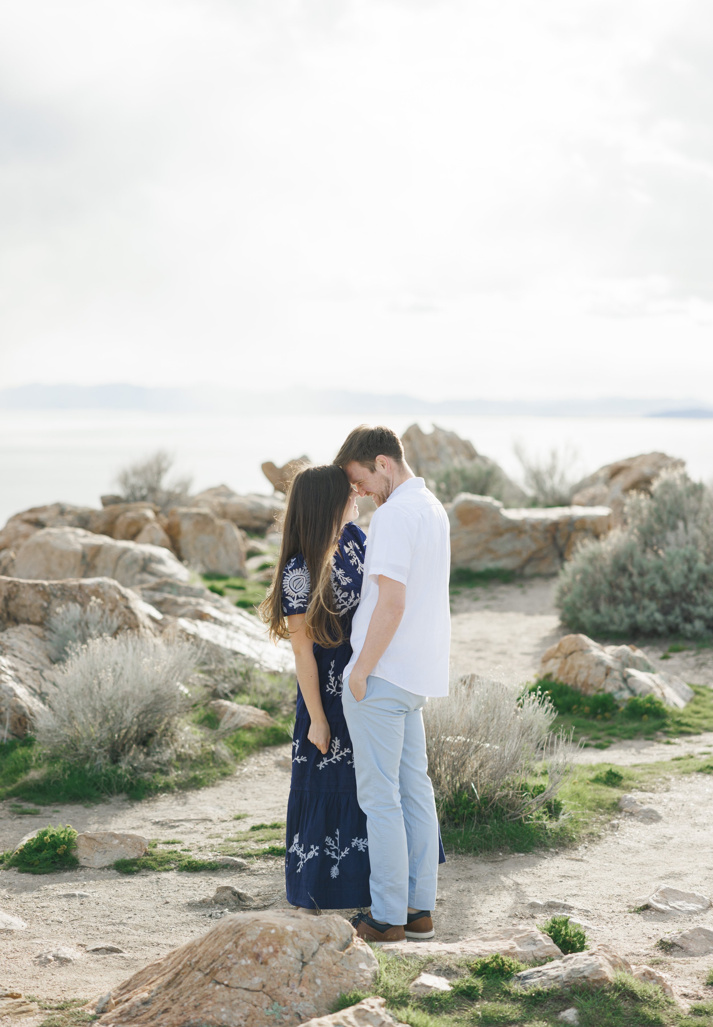  Overlooking the Great Salt Lake a couple stands on Antelope Island for engagements by Savanna Richardson PPhotograpphy. foreheads together pose high end engagements #SavannaRichardsonPhotography #SavannaRichardsonEngagements #UtahEngagements #Antelo
