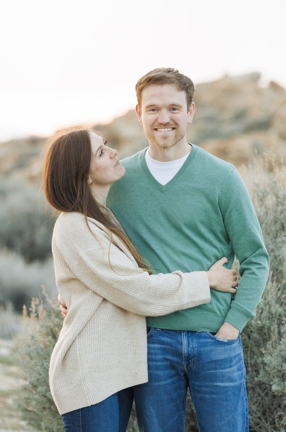  A woman looks lovingly up at her husband-to-be during sunset in Utah by Savanna Richardson Photography. green sweater sweaters for pictures sunset #SavannaRichardsonPhotography #SavannaRichardsonEngagements #UtahEngagements #AntelopeIsland #Springen