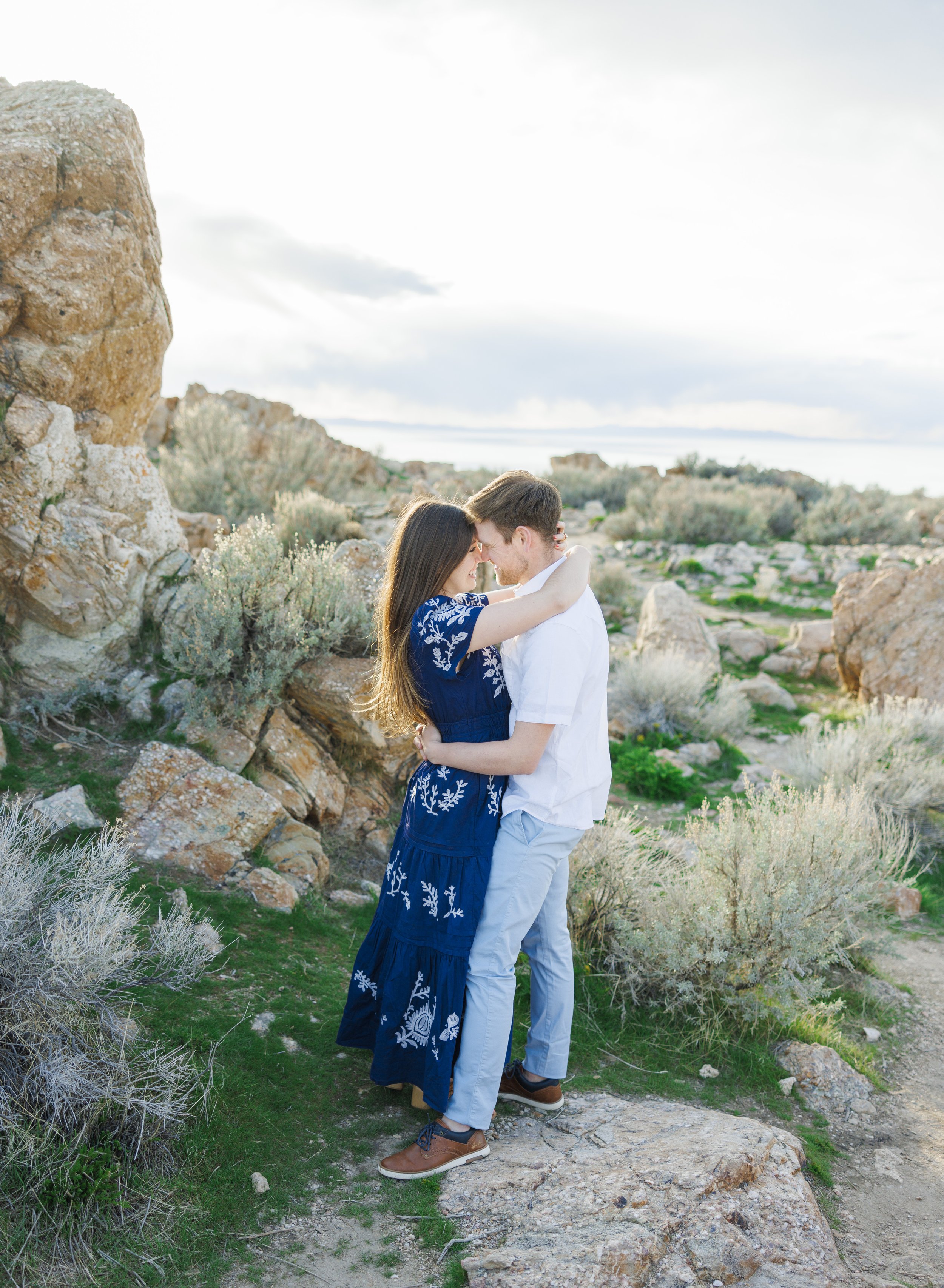  On a rocky mountain vista, a man and woman hug during an engagement session captured by Savanna Richardson Photography. engagement dreams spring engagement ideas #SavannaRichardsonPhotography #SavannaRichardsonEngagements #UtahEngagements #AntelopeI