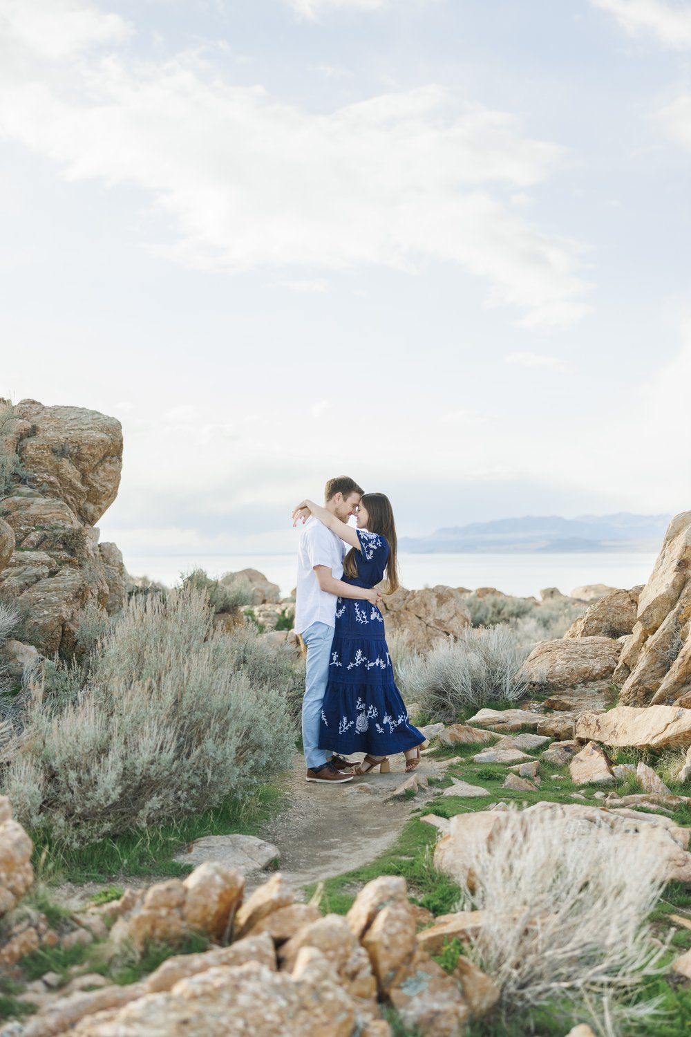  Newly engaged man and woman hug on Antelope Island featuring lake and sky behind them by Savanna Richardson Photography. lake engagement ideas outdoor Utah engagements #SavannaRichardsonPhotography #SavannaRichardsonEngagements #UtahEngagements #Ant