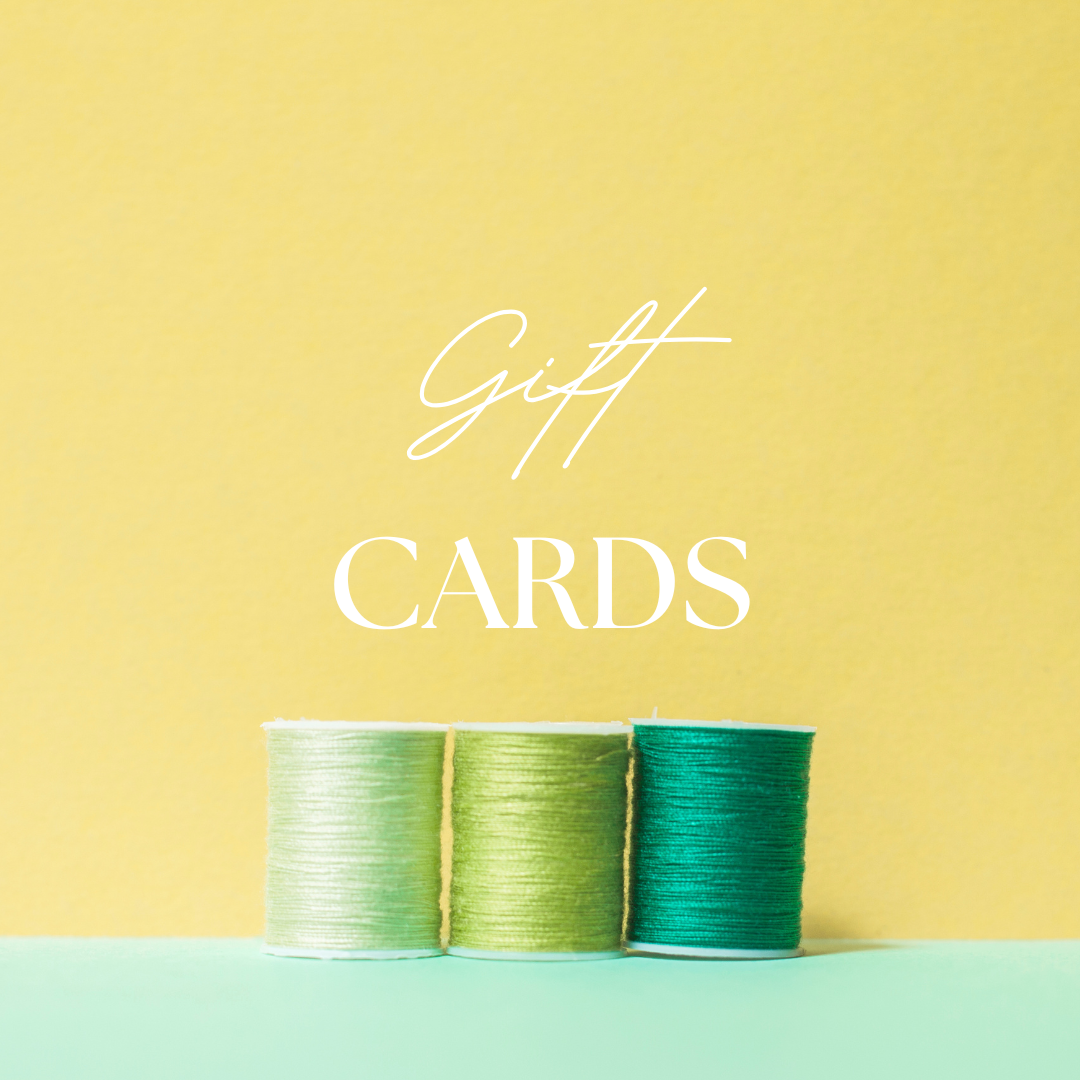 Three spools of green thread on light blue surface with yellow background, text overlay reading "Gift Cards"
