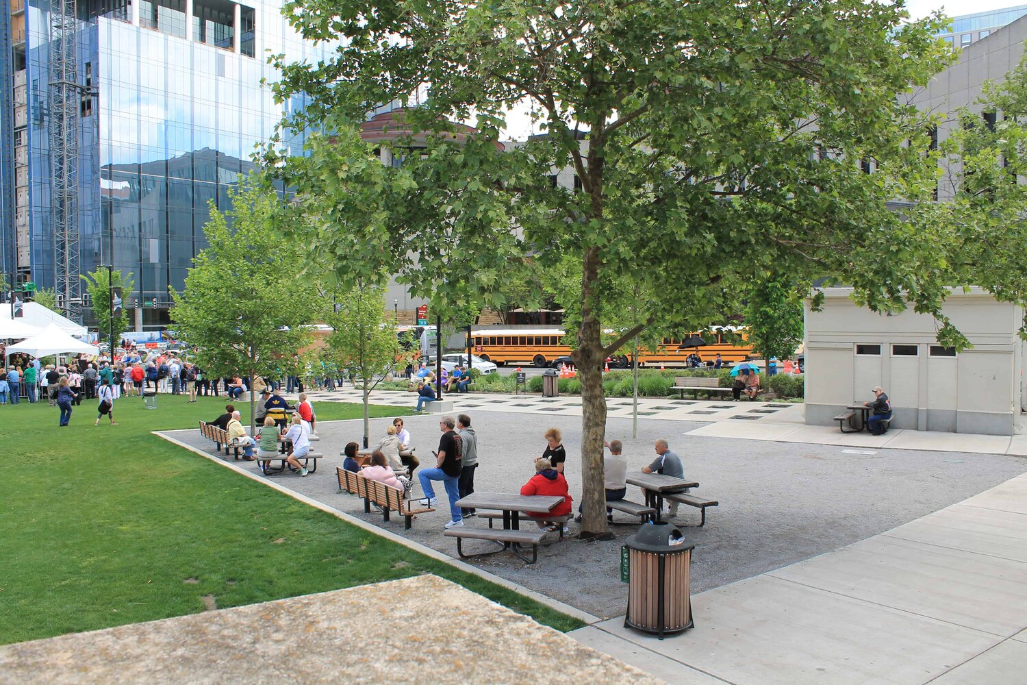 City dwellers enjoy a tranquil moment in the Walk of Fame park, surrounded by lush greenery and the bustling backdrop of high-rise buildings.