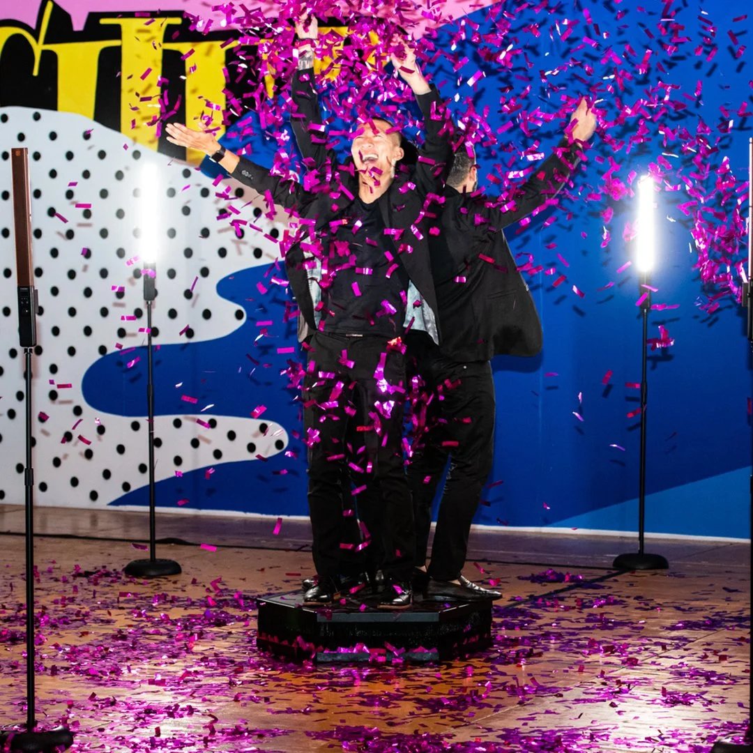 Guests celebrating inside an interactive 360 photo booth with confetti effects and cinematic video capture during a high-energy corporate or wedding event.