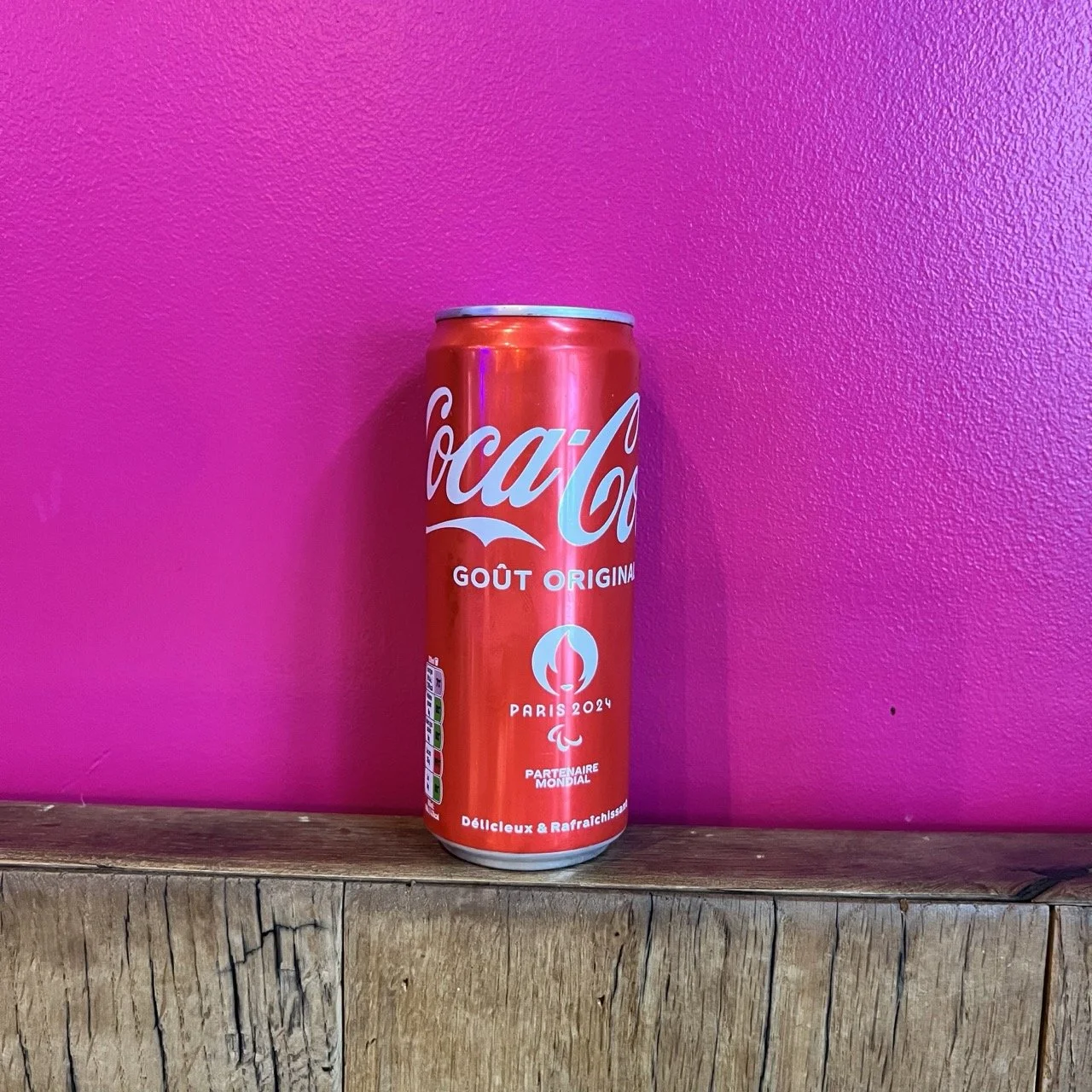 Canette de Coca-Cola avec logo Paris 2024 sur fond rose.