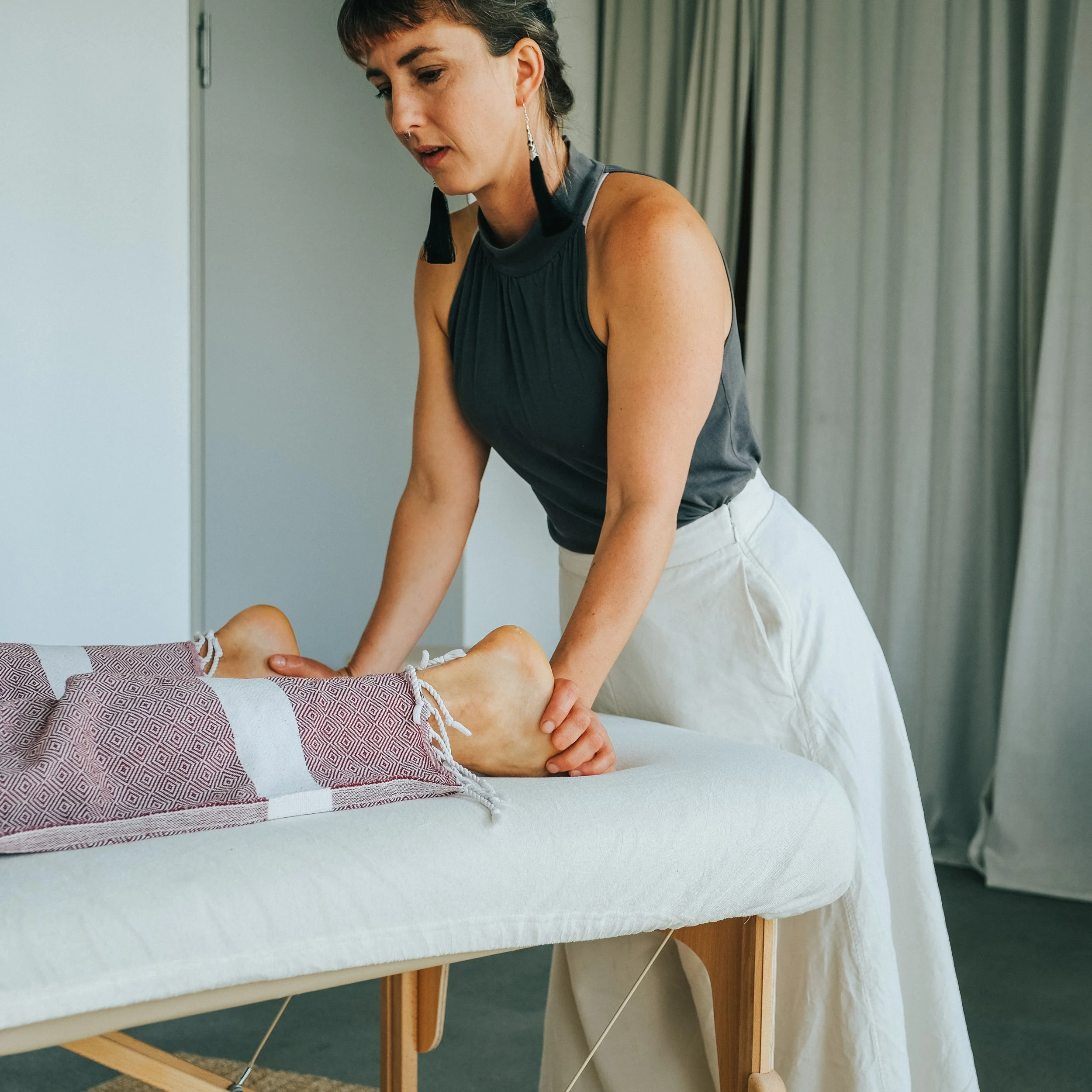 A massage therapist giving a massage to a client's foot on a massage table.
