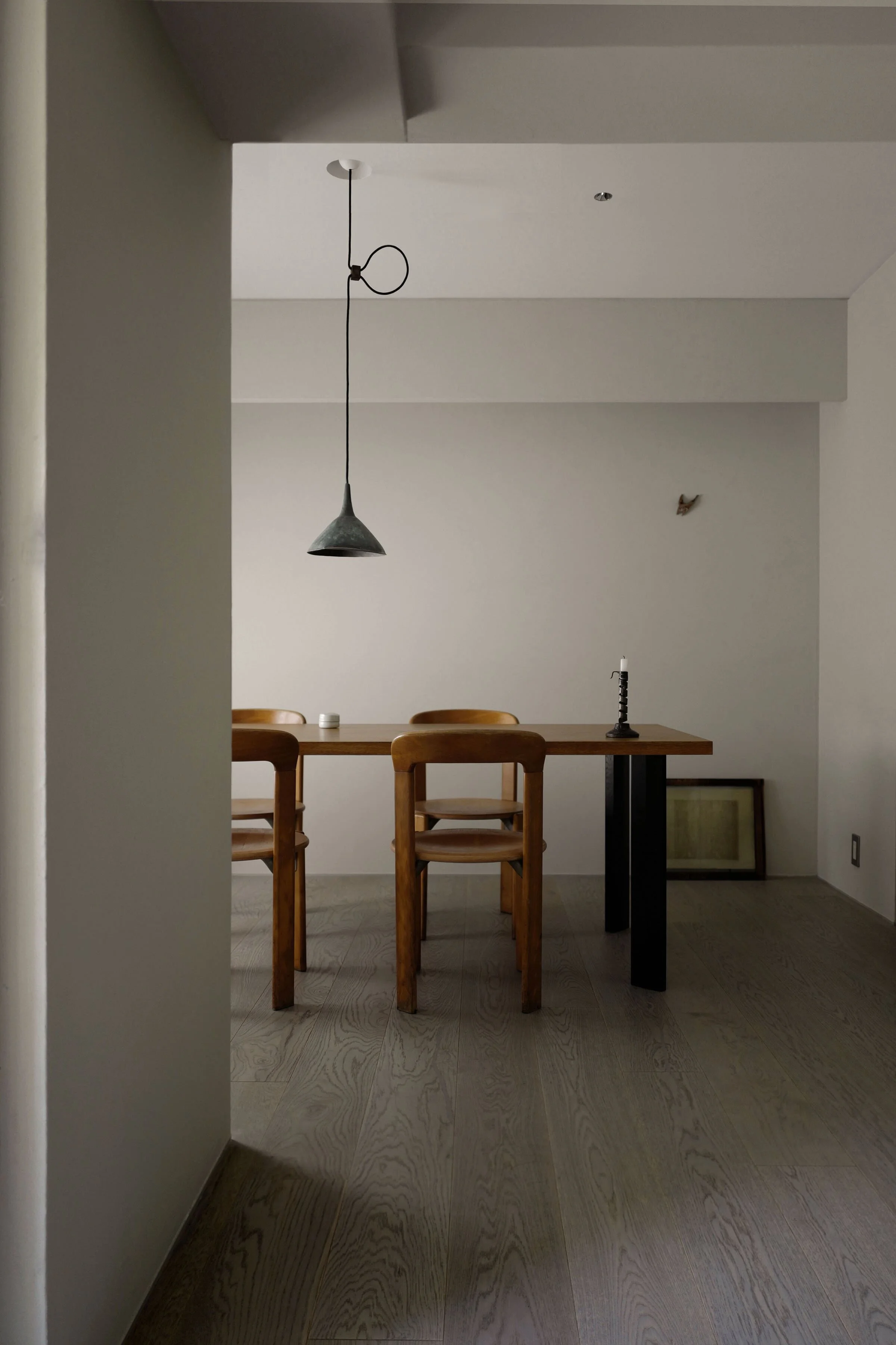 正面奥の垂れ壁は、既存ダクトの存在を隠し、さらに壁に柔らかな影を落とすためにダクトの下端よりも下まで伸ばしたデザイン。ペンダントライトは、古道具をカスタマイズしたもの。