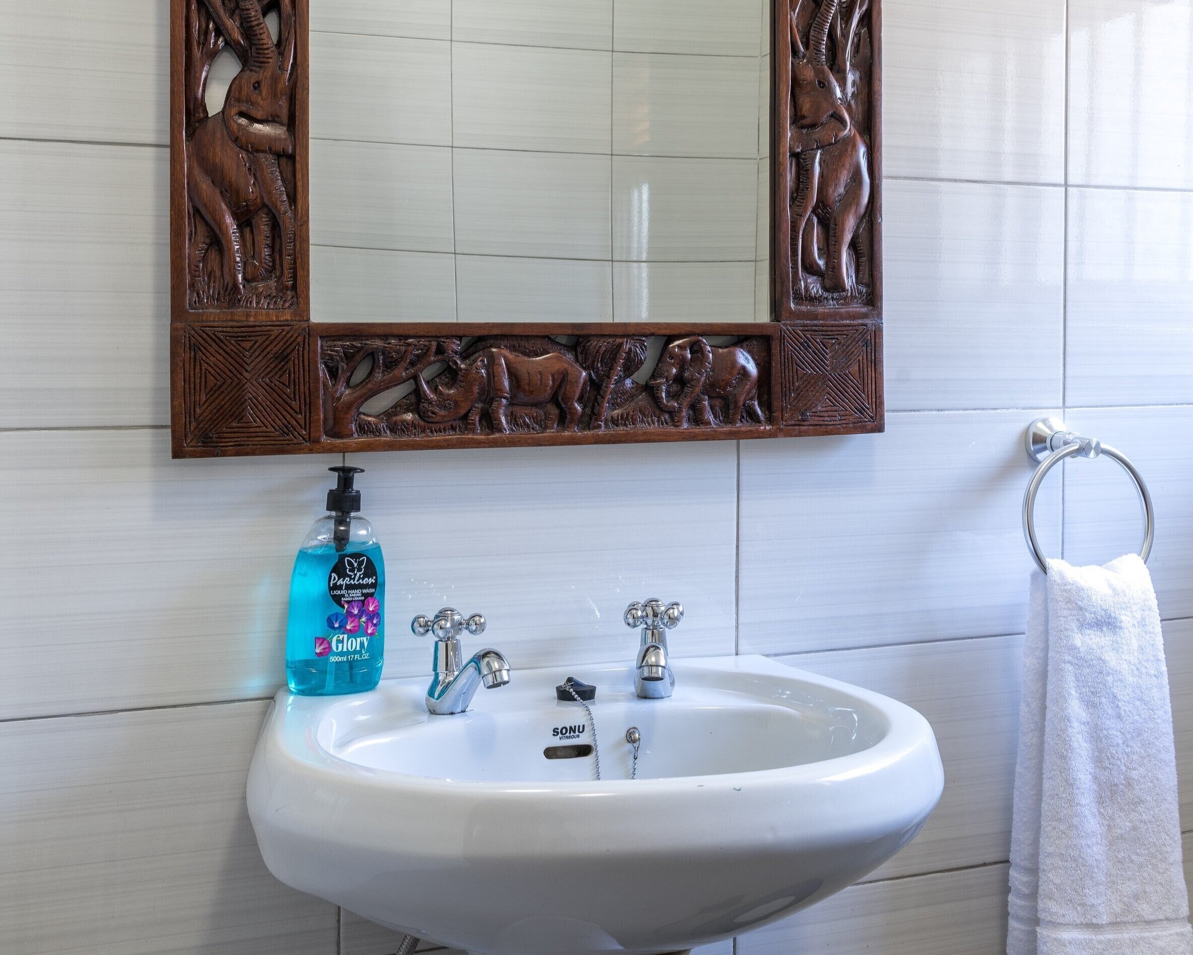 bathroom with African craft mirror, sink and towel rail 