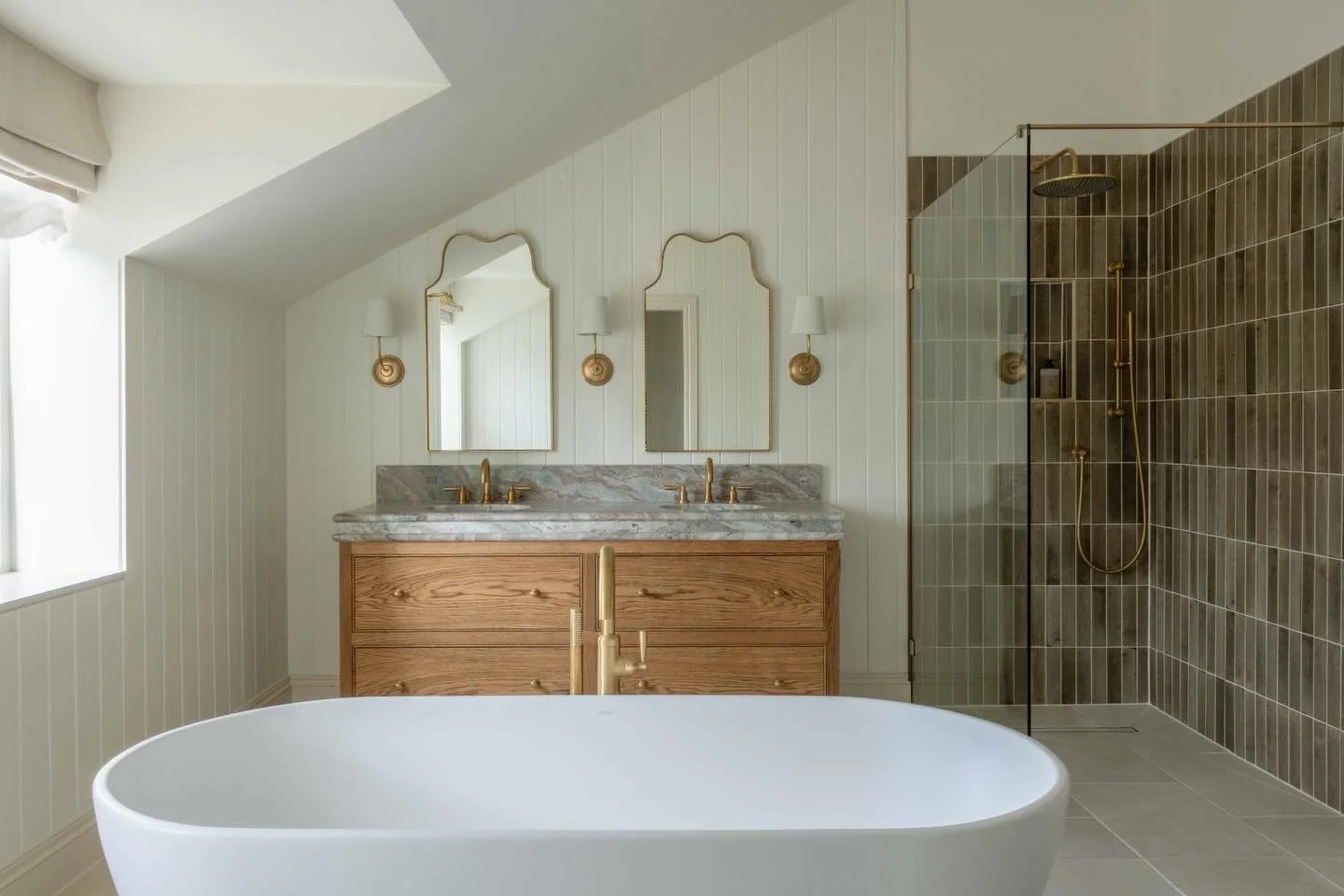 Soft light, warm wood, and brushed brass details ✨
⠀⠀⠀⠀⠀⠀⠀⠀⠀
This bathroom is a masterclass in calm, considered design. From the freestanding tub perfectly placed under the vaulted ceiling to the rich timber vanity topped with marble, every element f