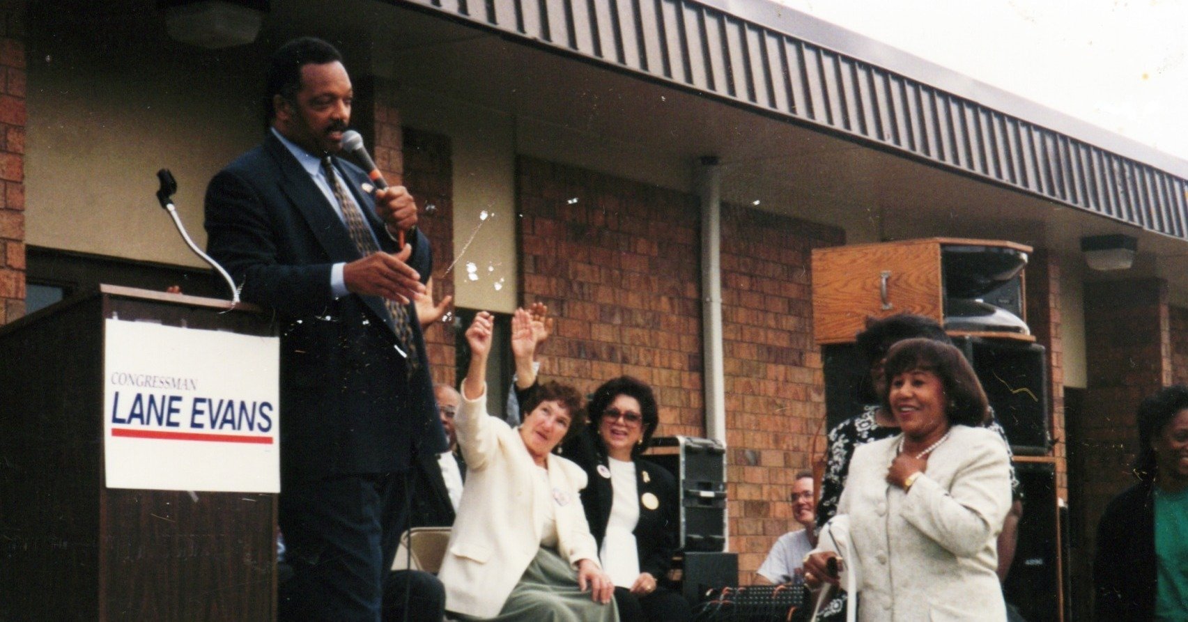 Jesse Jackson speaks at a podium outside the Martin Luther King Jr Community Center in Rock Island, Illinois encouraging voter registration in 1996.