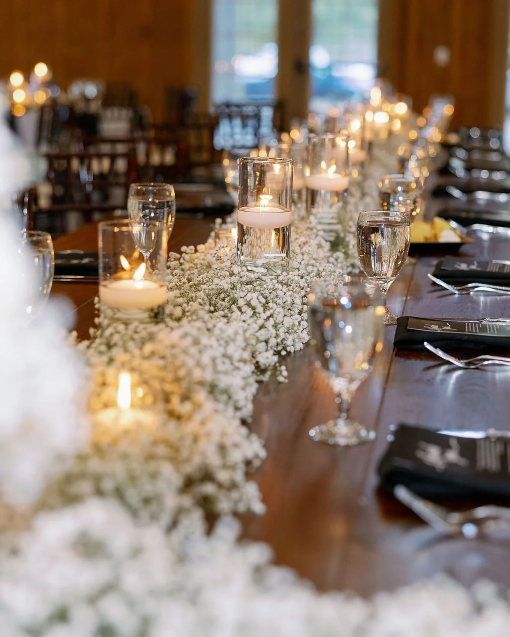 These amazing clouds of baby's breath look stunning accenting our farm tables! Mixed with floating candles in clear glass cylinders, it's a classic and elegant look for this black and white themed wedding.

@gaigelancaster_photography
@theperfectpebb