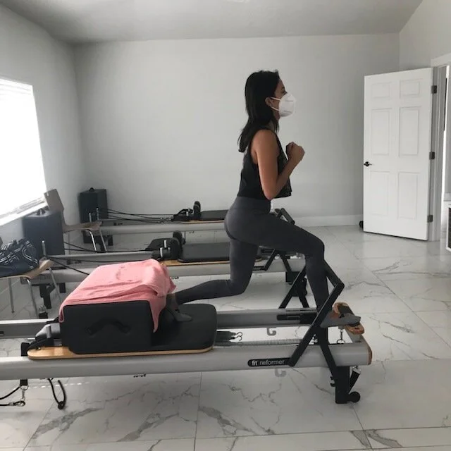 Client performing a standing lunge on a Pilates reformer at Renegade Pilates in Miami