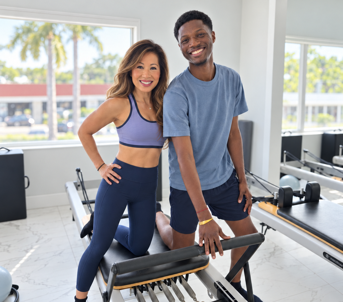 Smiling woman and man posing on a Pilates reformer after class at Renegade Pilates in Miami.