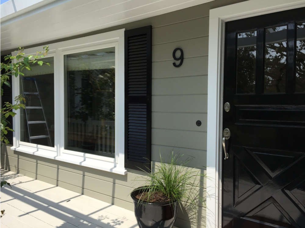 Green House With Black Front Door And Strom Shutters