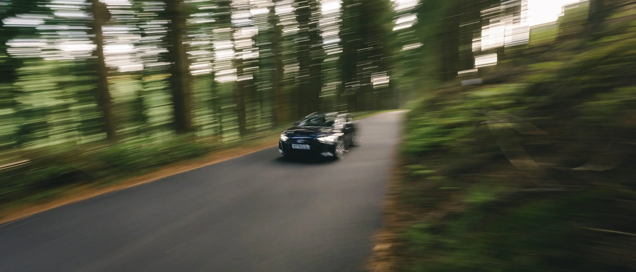 Panning shot of an Audi on a forest road, Wales