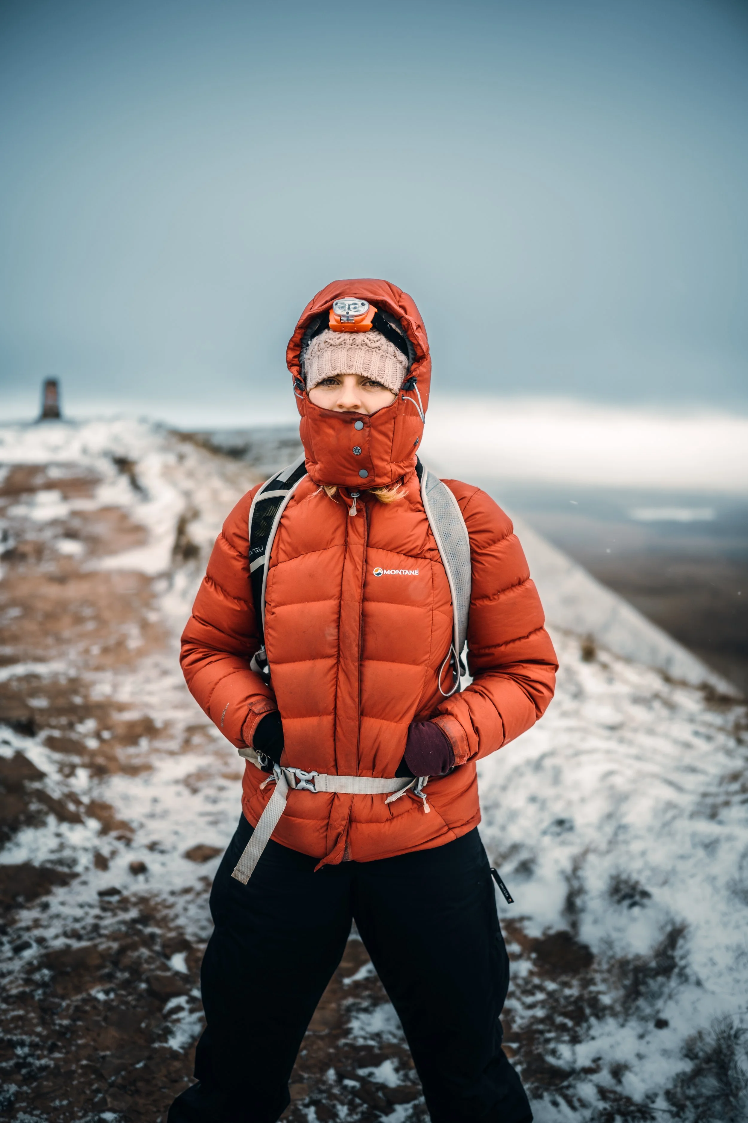 Hiker in an orange down jacket on a snowy summit
