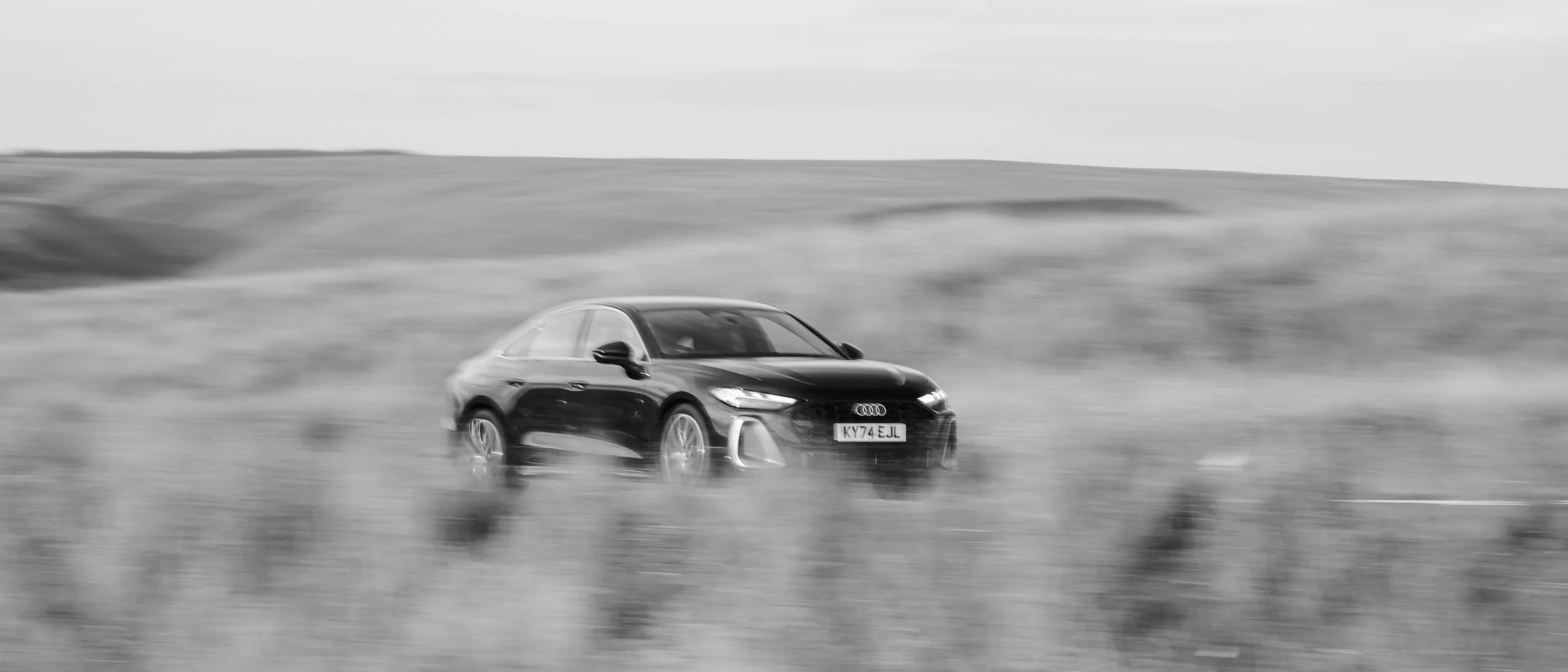 Black Audi on a moorland road in black and white, Wales