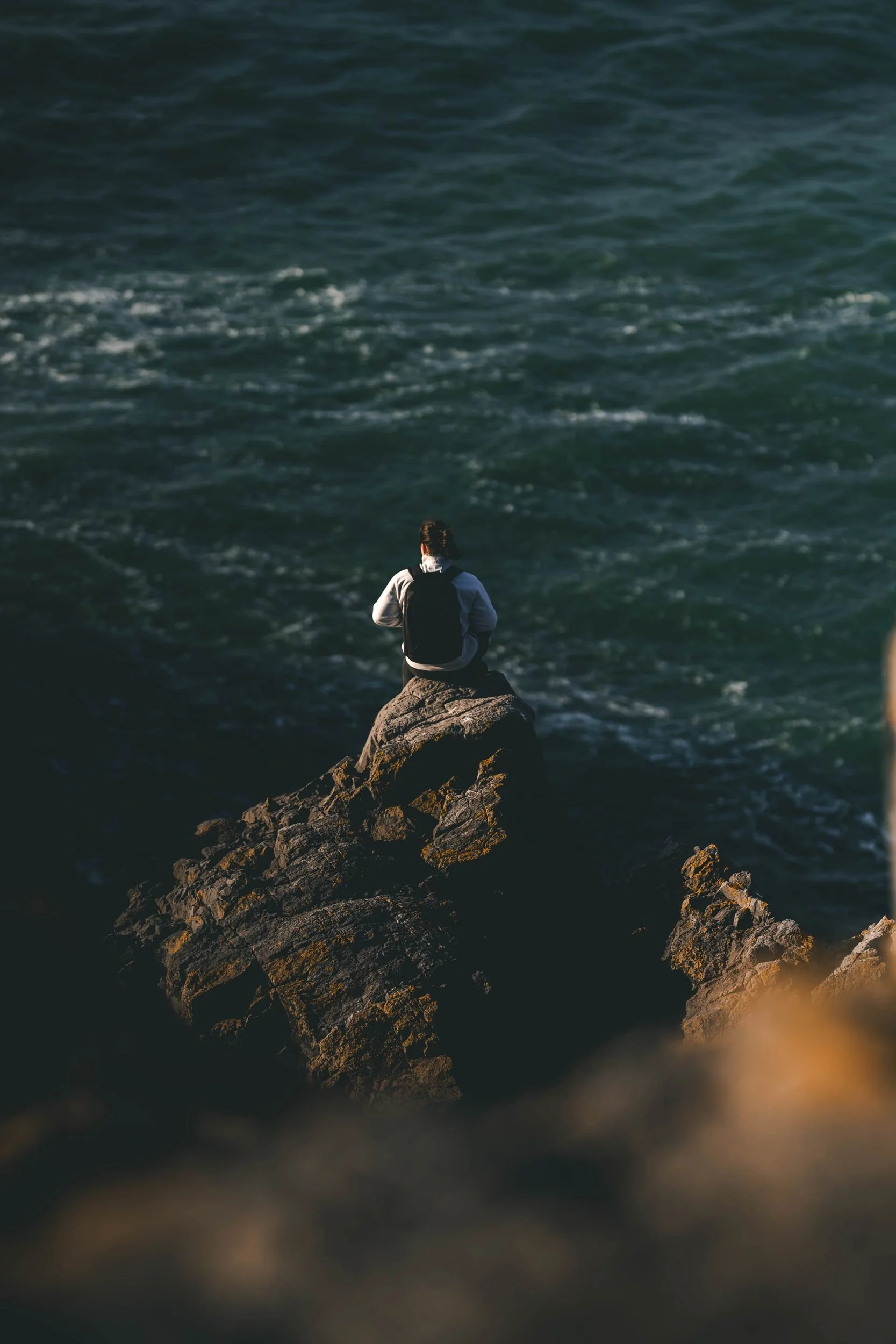 Figure perched on sea cliffs above the swell, Pembrokeshire