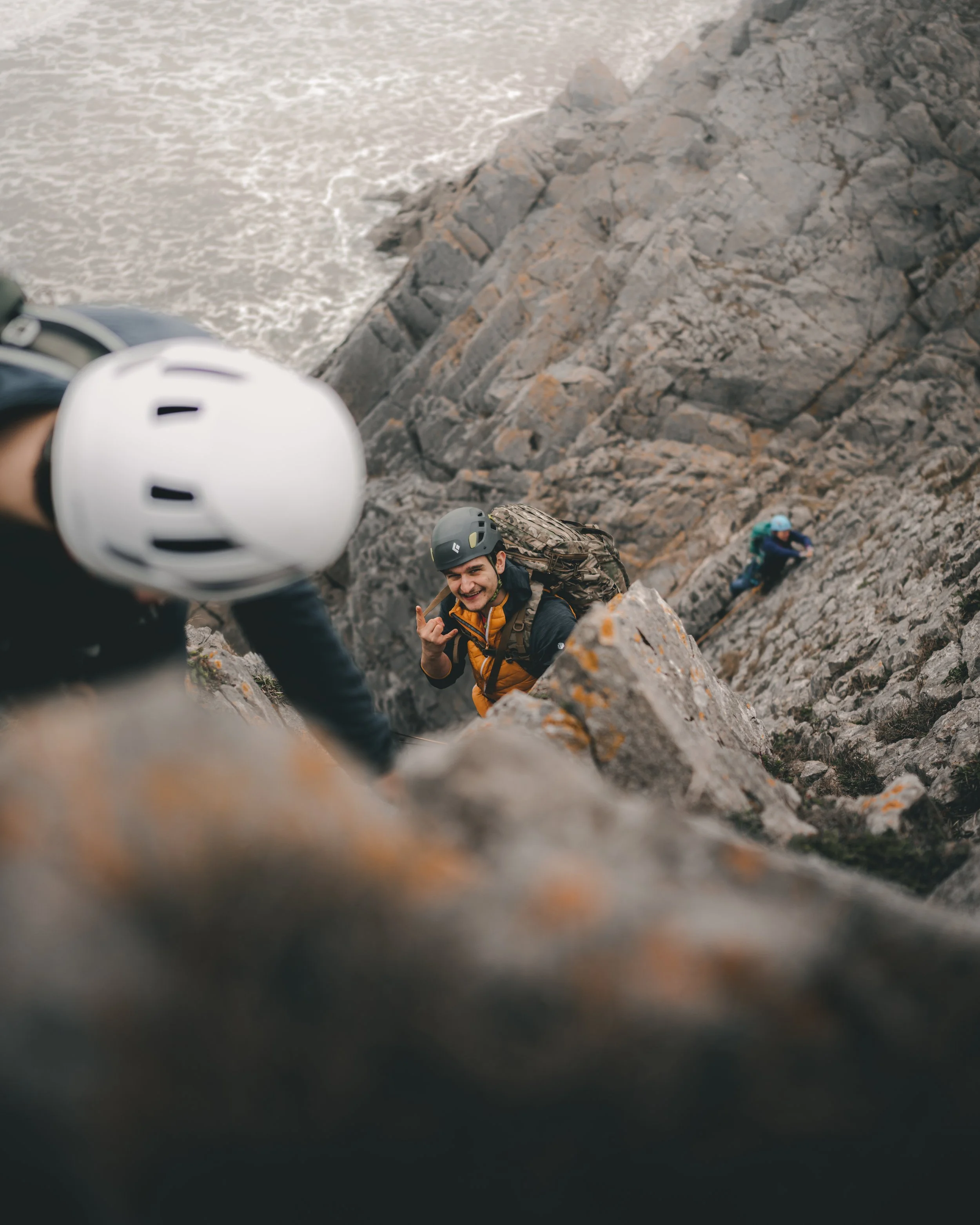 Climbers on a rocky ridge seen past a helmet