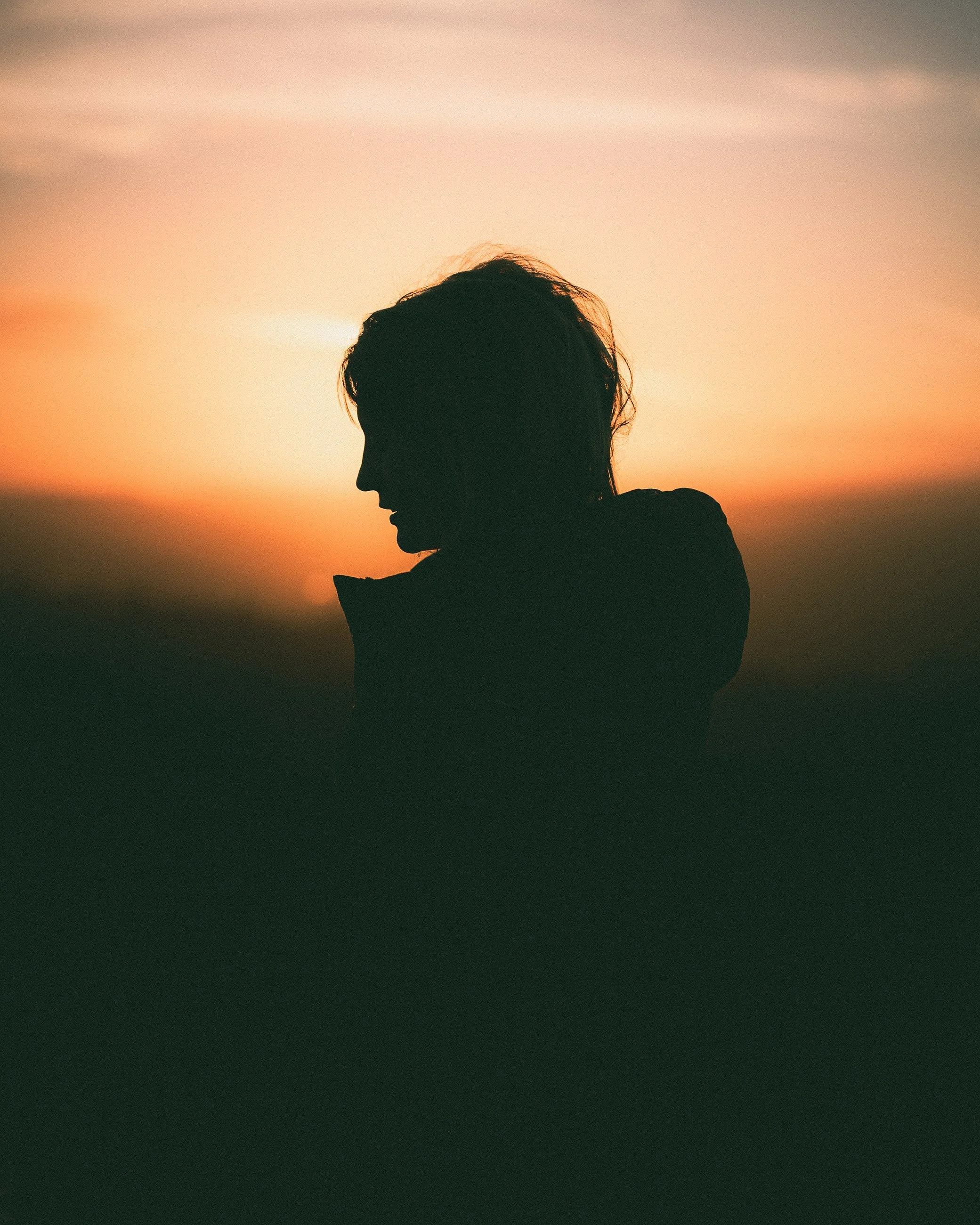 Silhouette of a woman against an orange sunset