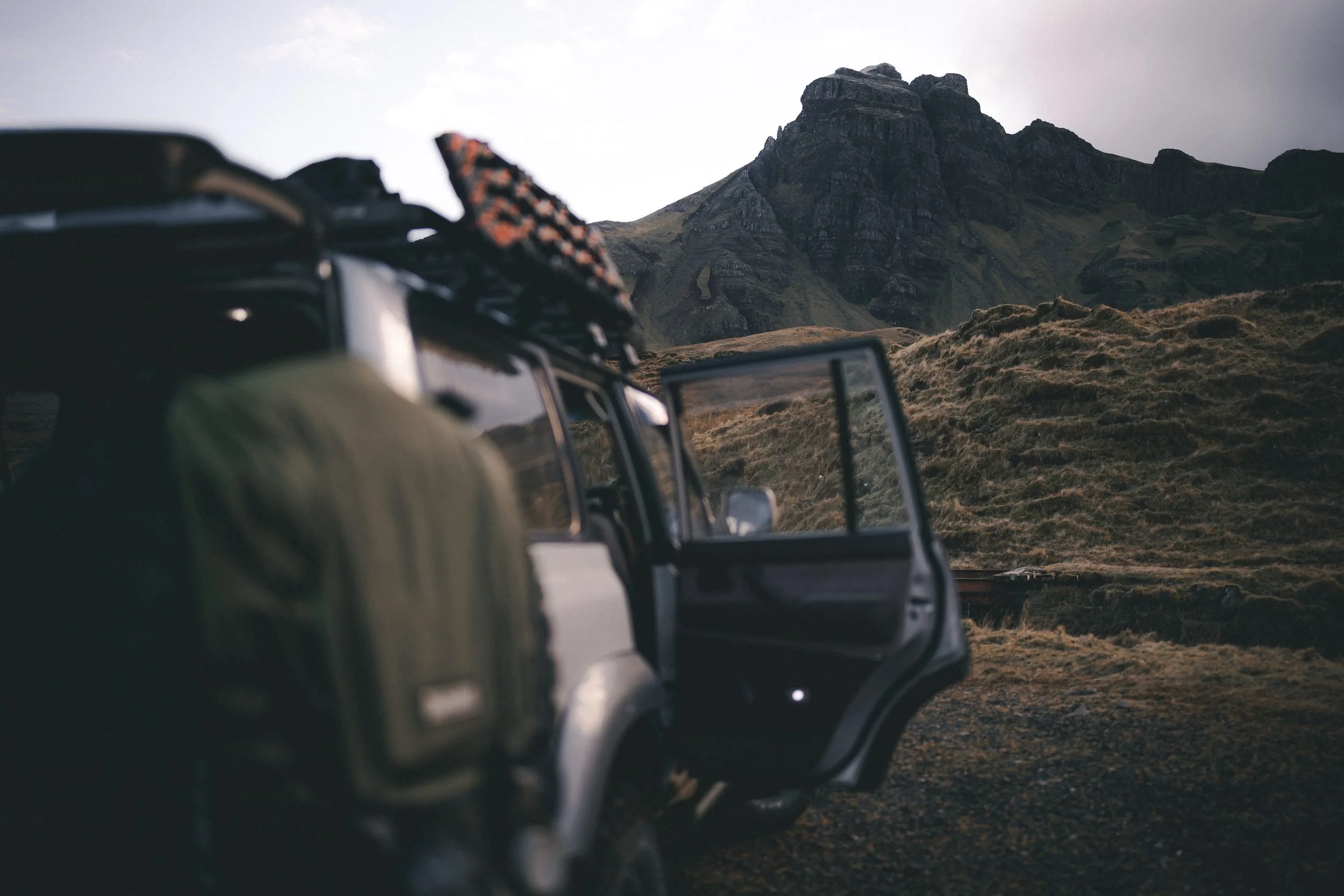 Land Cruiser 80 Series with its door open below a rocky peak, Hill of the Red Fox, Isle of Skye