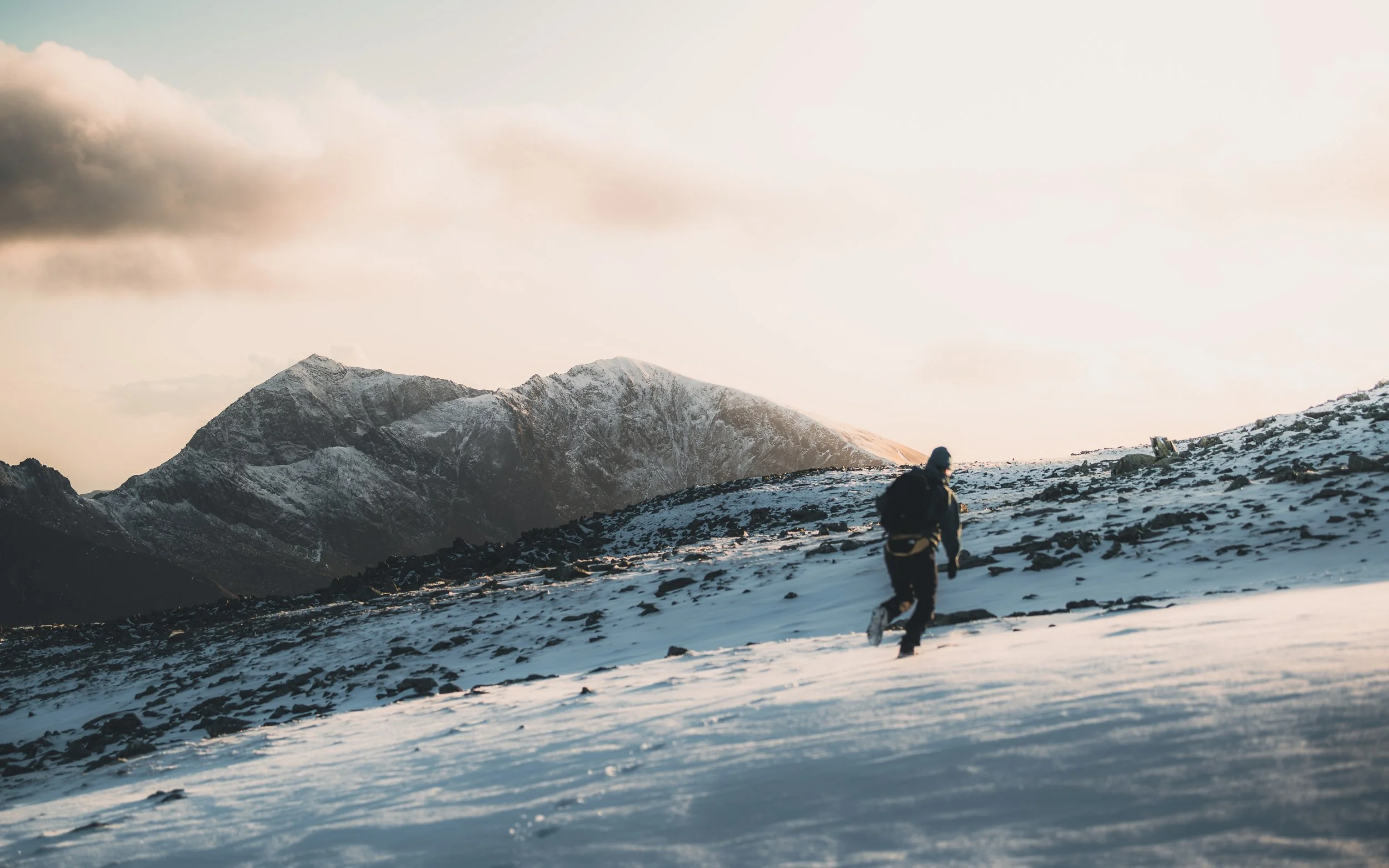 Hiker crossing a snowy ridge at sunrise