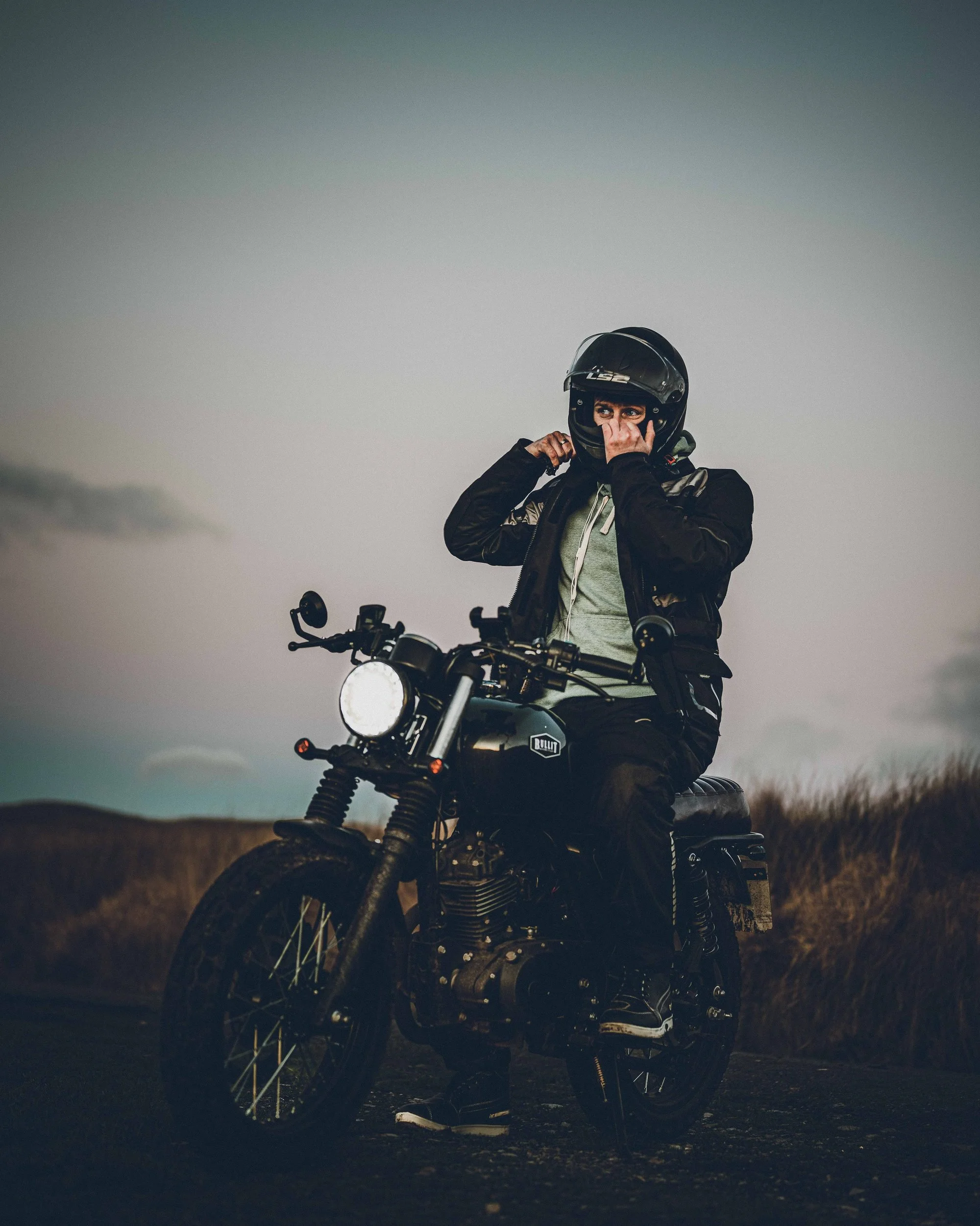 Rider pulling on his helmet on a Bullit motorcycle, Bannau Brycheiniog