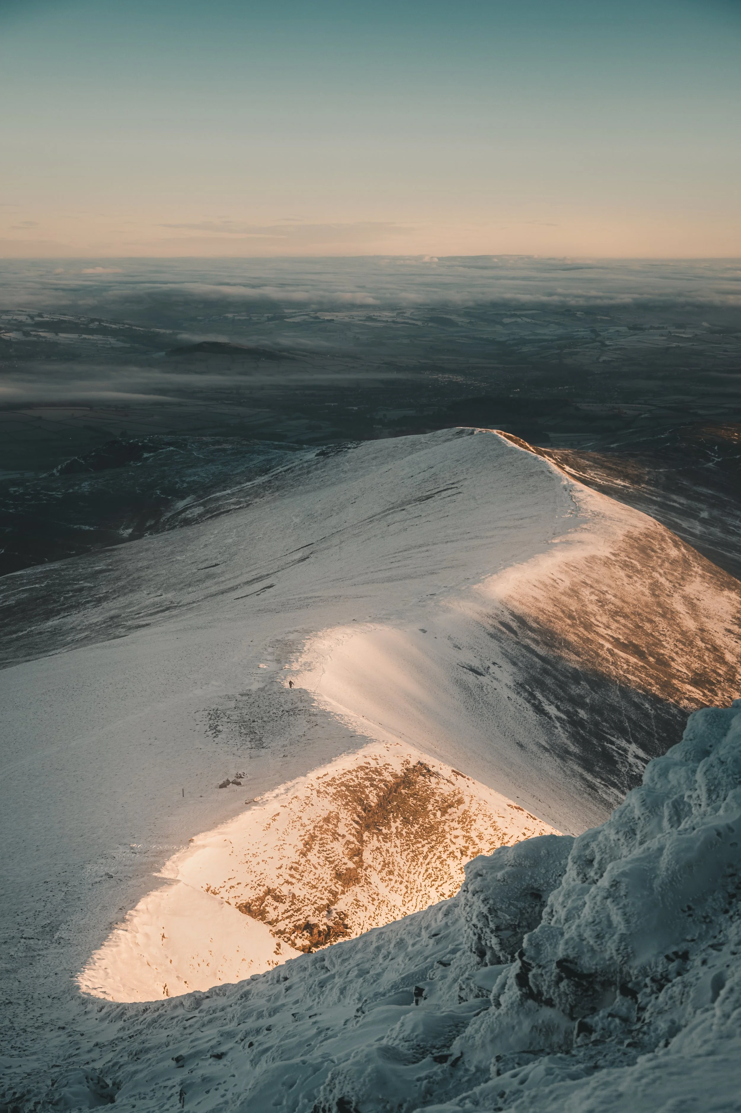 Sunlit snowy ridge above a sea of cloud
