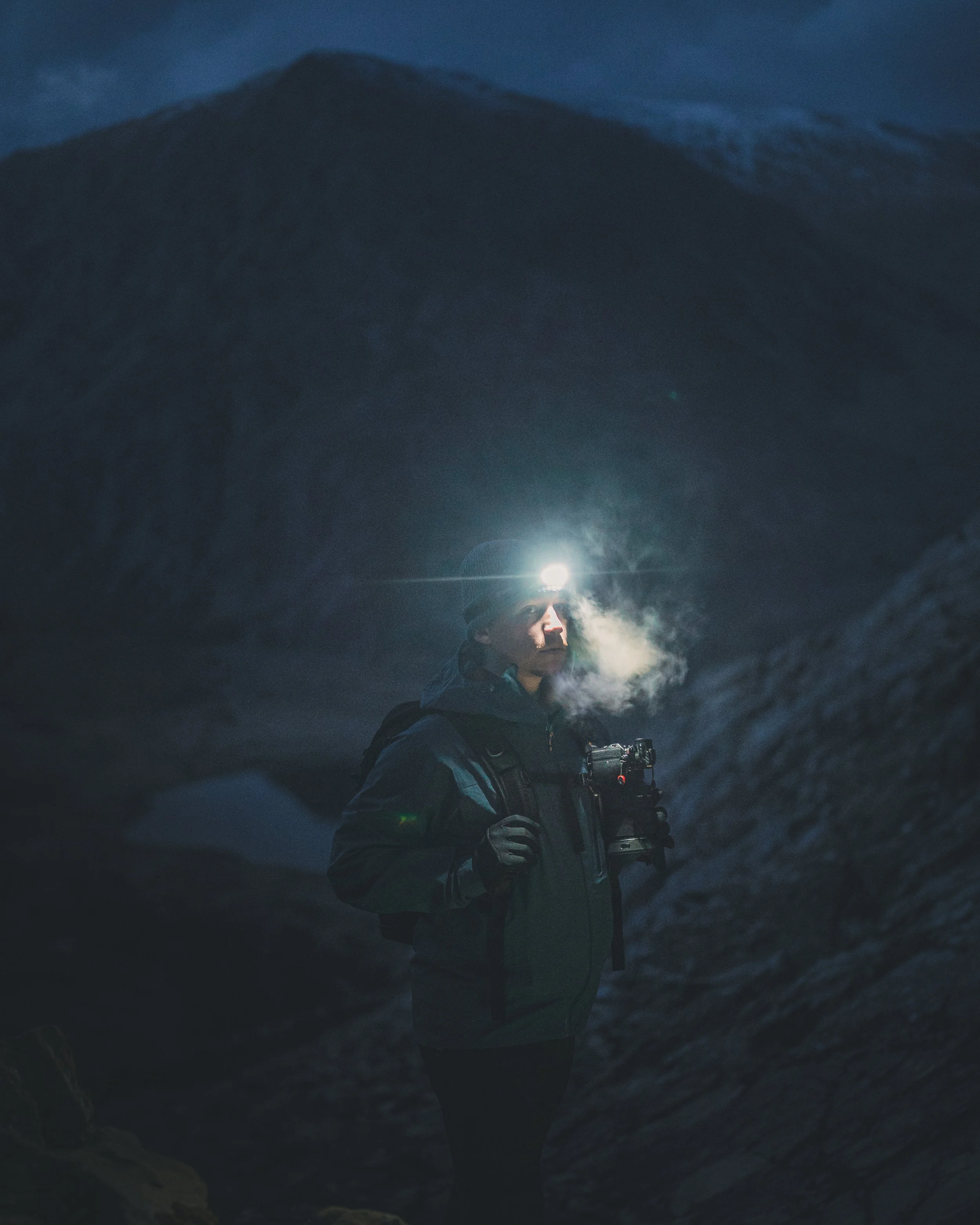 Hiker with a head torch on a mountain at night