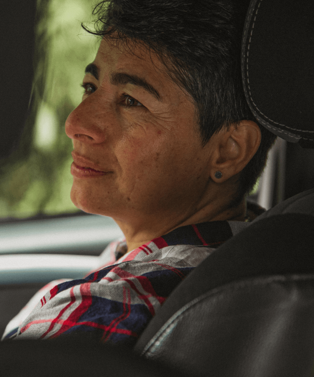 an image of a woman in the passenger seat of the car, she is looking at the driver with a smile and a caring look on her face.