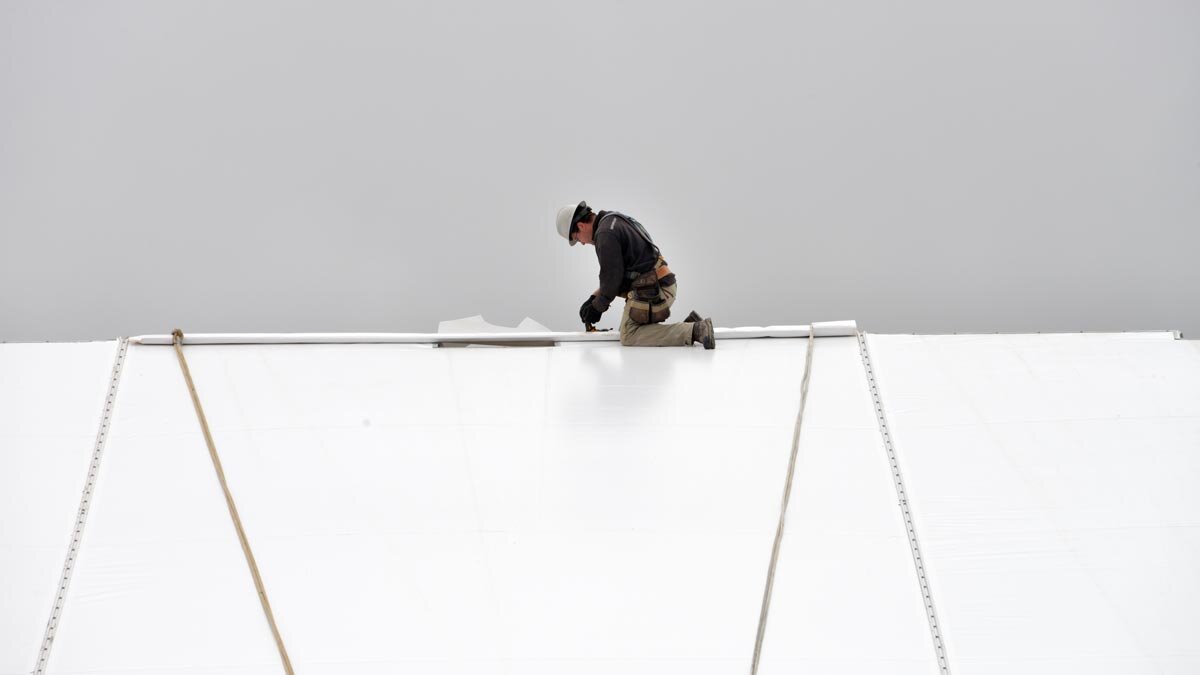  A contractor working on top of a fabric roof barn. 