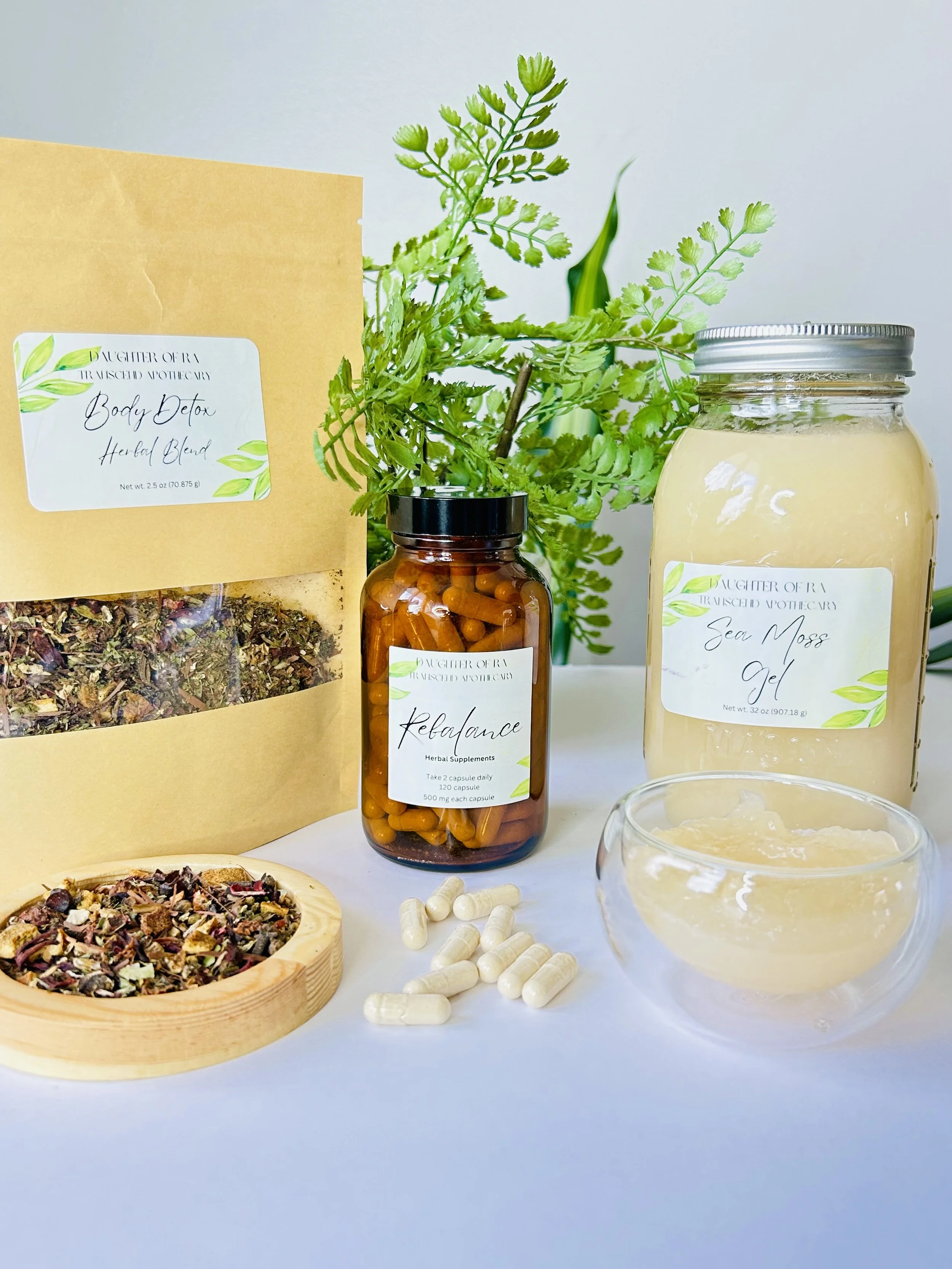 Herbal products including a bag of body detox herbal blend, sea moss gel in a jar, herbal supplements in a bottle, and loose herbal mixture in a wooden bowl, with green herbs in the background.