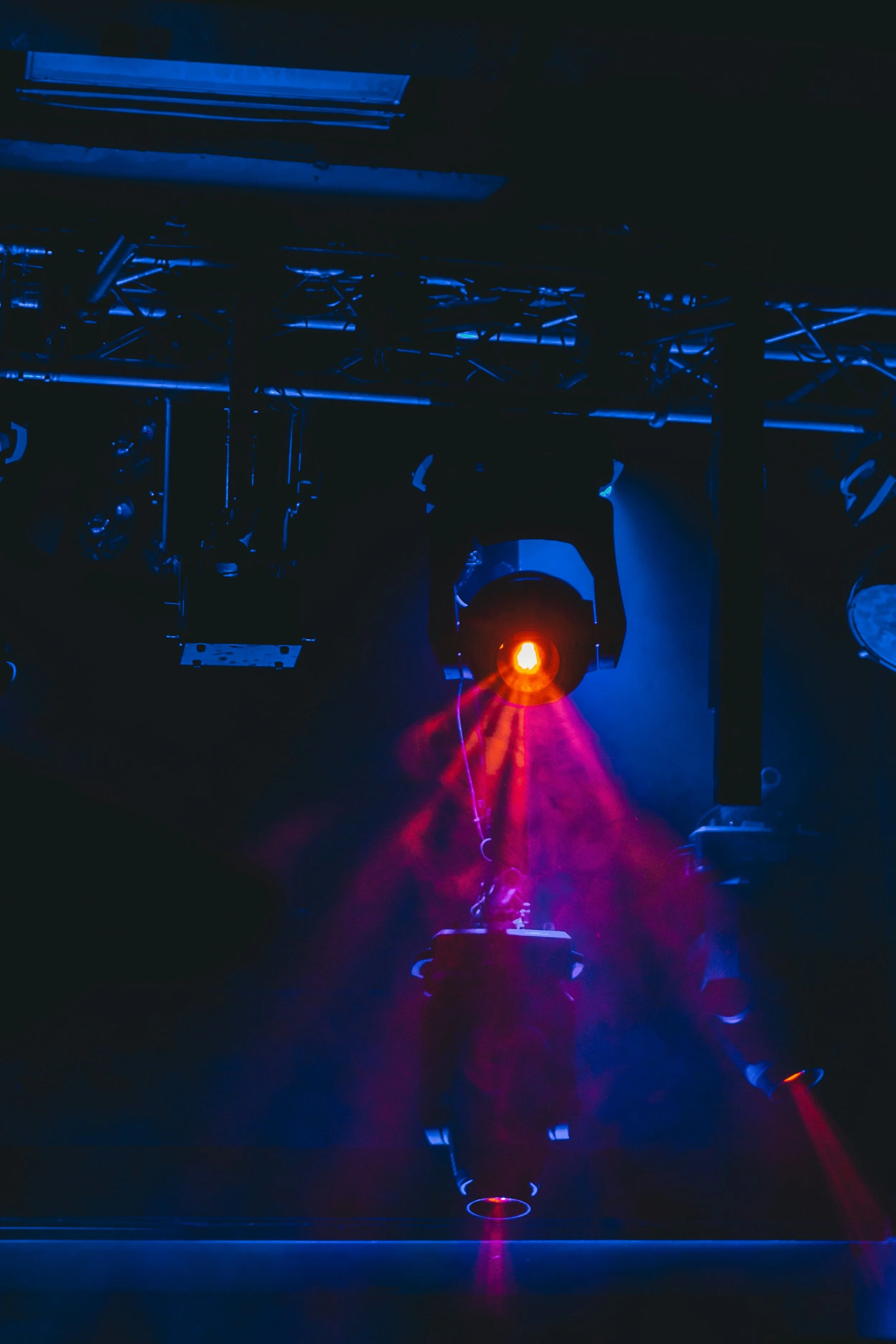 A robotic arm with a laser light working in a dark environment, illuminated with blue and purple hues.
