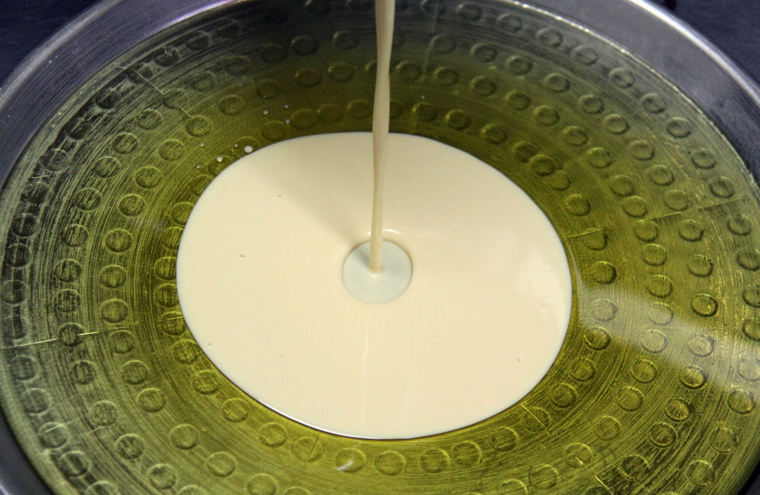 Pouring farinata batter into a traditional pan