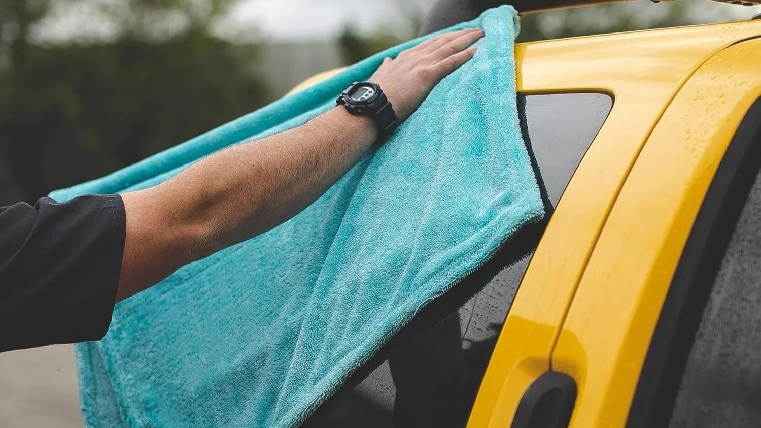 Car being hand washed in San Diego driveway showing proper washing technique with microfiber mitt