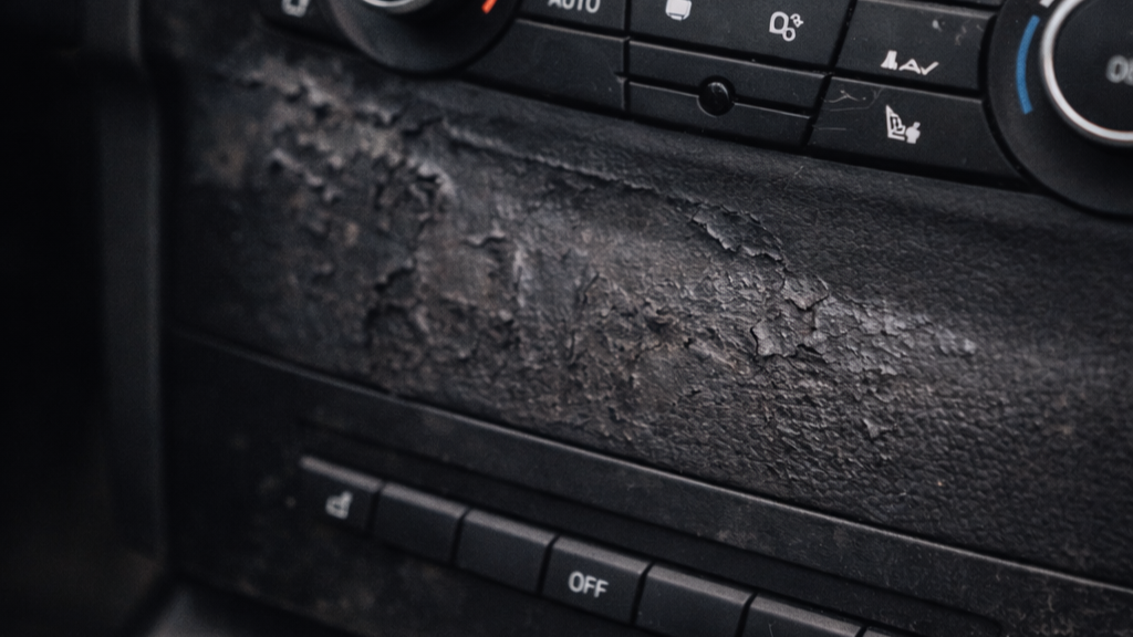Car dashboard showing sticky soft-touch plastic degradation on center console