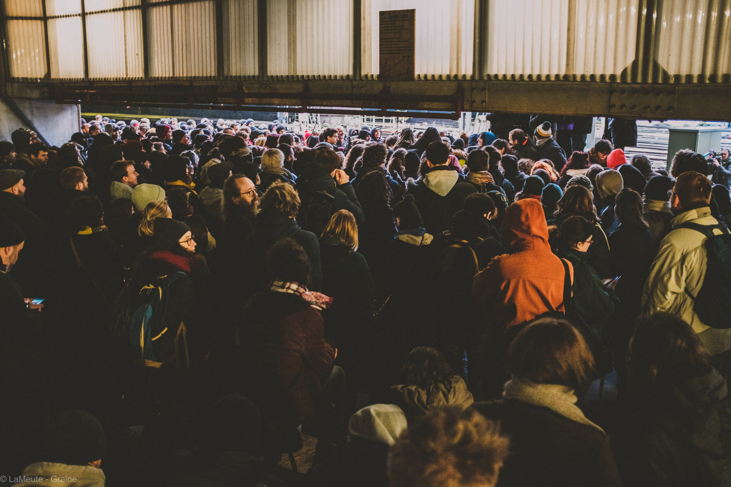  Plusieurs centaines de personnes assistent à l’assemblée générale, les yeux rivés sur la tribune à laquelle tout le monde peut s’exprimer. © LaMeute - Graine 