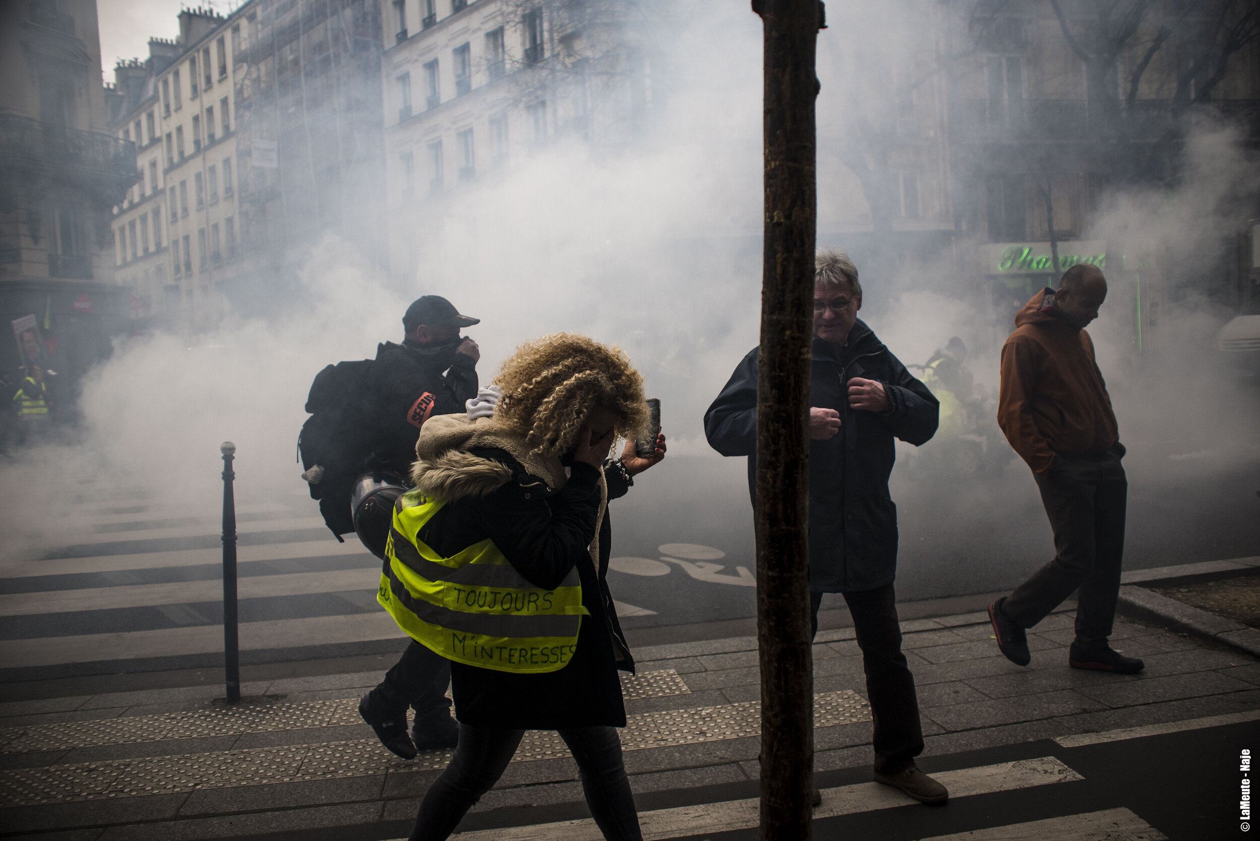   Une femme Gilet Jaune essaye de s’éloigner de la fumée des gaz lacrymogènes.  ©LaMeute - Naje.      