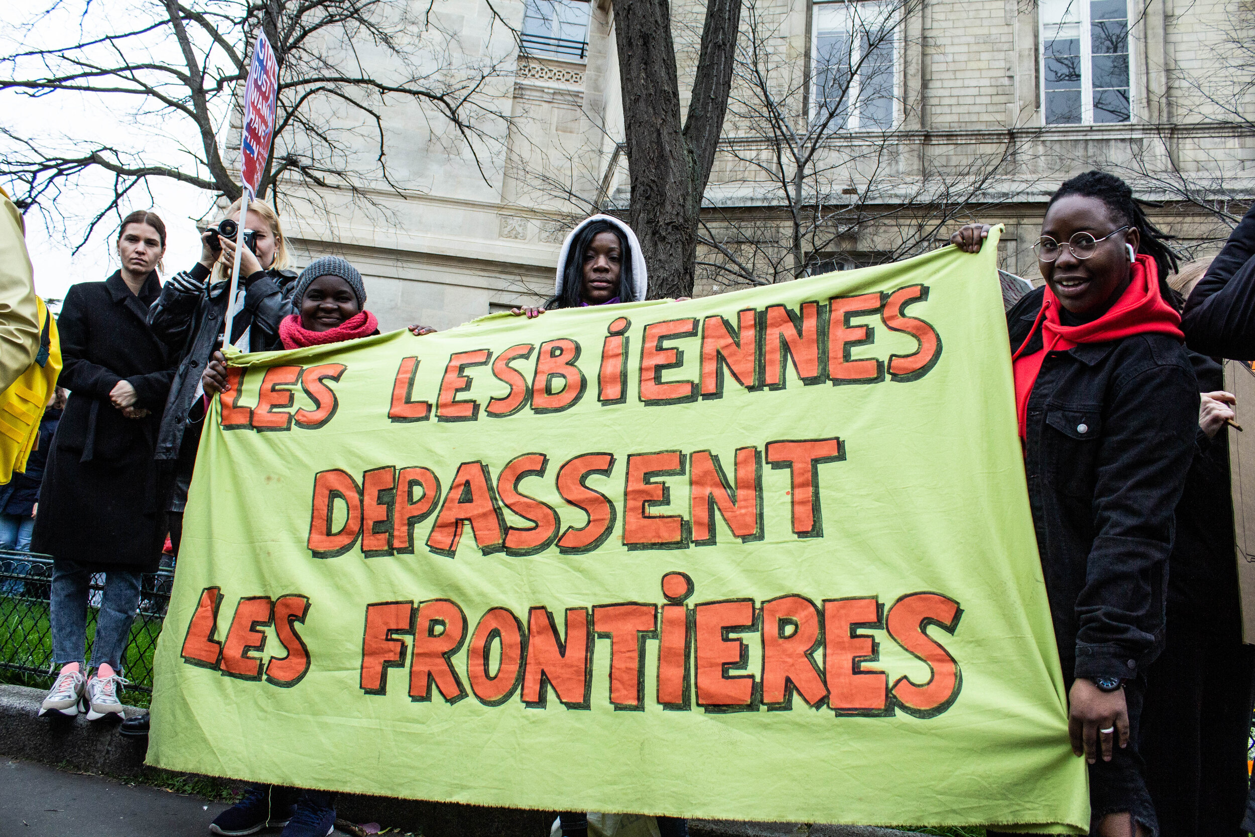   Trois manifestantes et leur banderole « Les lesbiennes dépassent les frontières » à la journée internationale des luttes pour les droits des femmes, Place d’Italie.  ©Krioula 