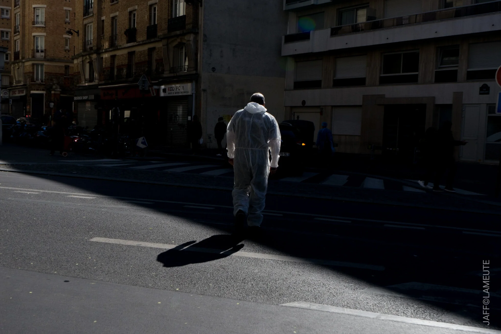Un ambulancier dans une combinaison blanche traverse pour rejoindre son ambulance. © LaMeute - Jaff
