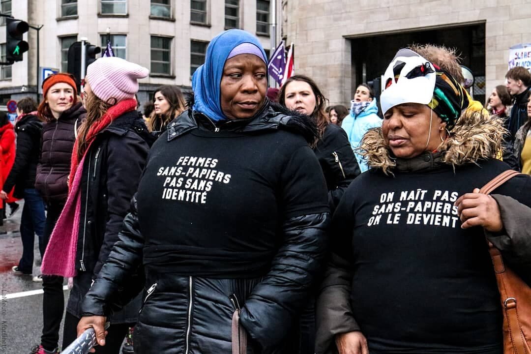   Des manifestantes portent des t-shirts en soutien aux femmes sans-papiers. Déshumanisées et invisibilisées par les pouvoirs politiques et médiatiques, ces femmes représentent plus de 40% des exilé.es en Belgique et voient leurs droits élémentaires 