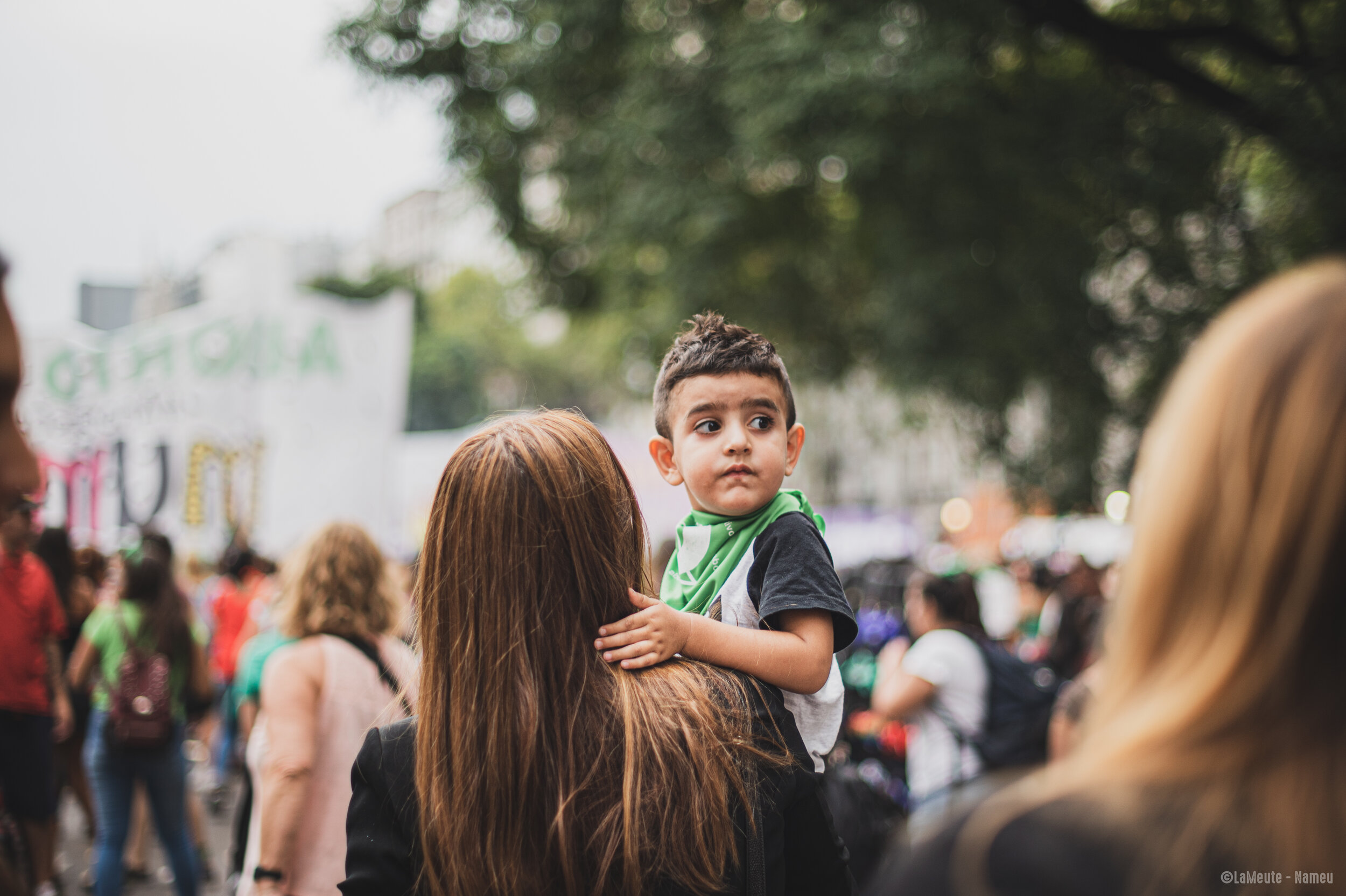   Une manifestante marche avec son fils dans les bras. Lui aussi porte un foulard vert en référence à la légalisation de l'avortement. « La maternité sera souhaitée ou ne sera pas ».  ©LaMeute – Nameu 