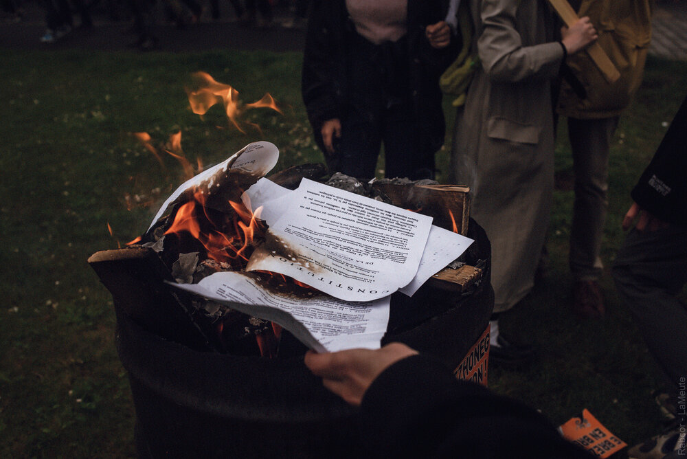  Des manifestant.e.s brûlent l’article de la constitution qui fait référence à celui invoqué pour censuré la loi Molac. 