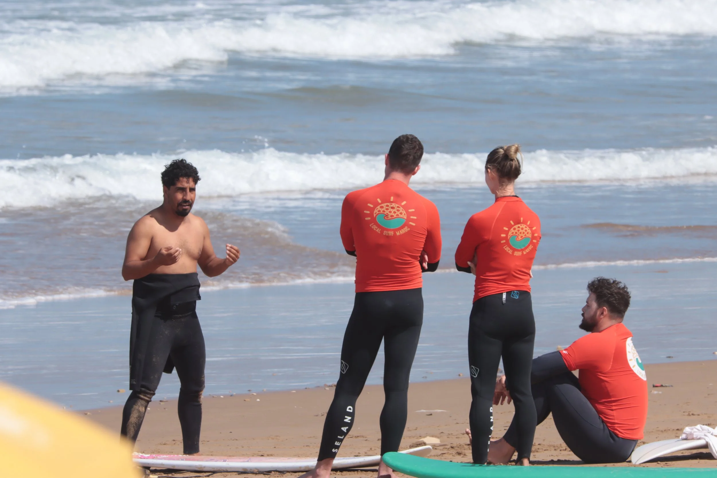 Rachid teaching a small group of intermediate surfers some theory on the beach Taghazout, Morocco.